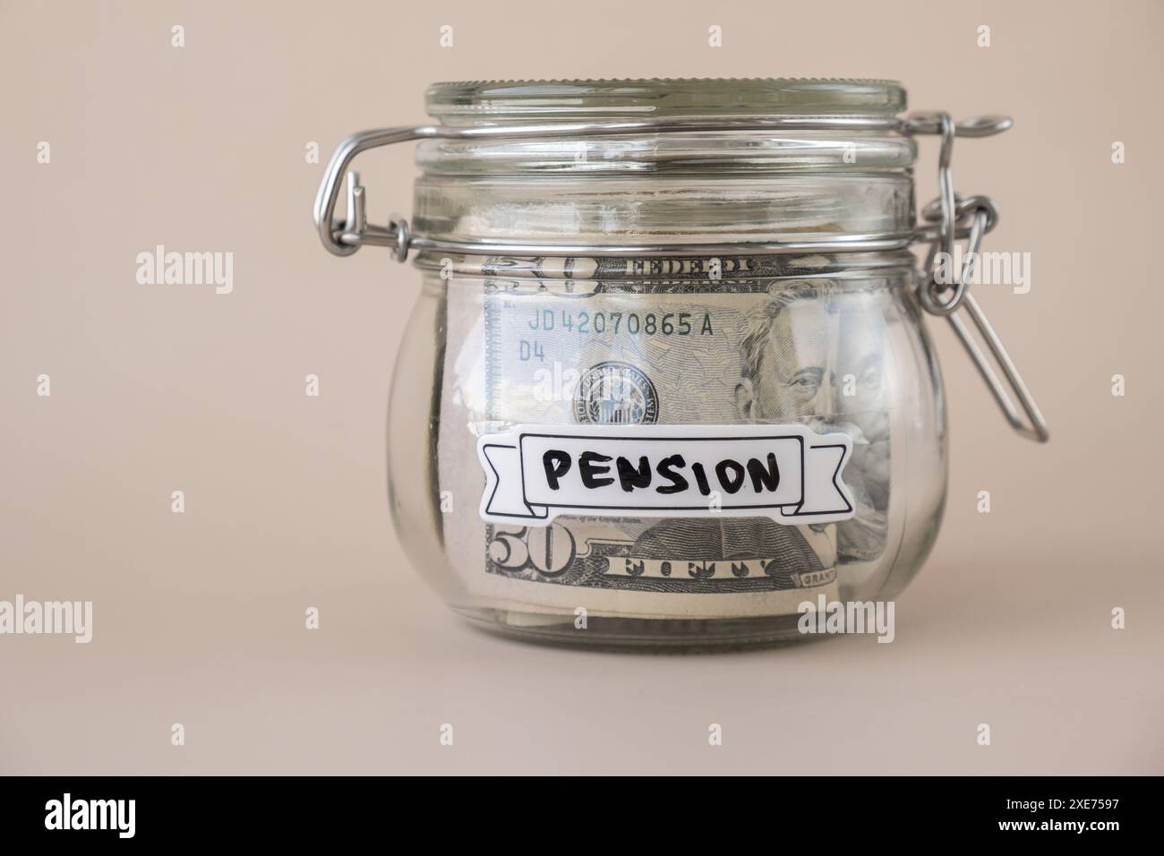 Barattolo di vetro pieno di banconote in dollari americani con PENSIONE testuale. La preparazione consente di risparmiare denaro. Consumo moderato e. Foto Stock