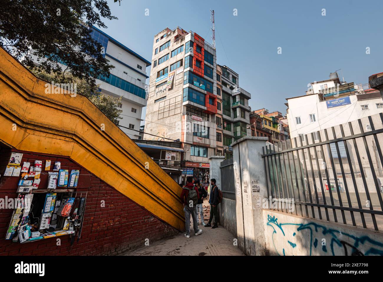 Ponte pedonale giallo e recinzioni che conducono l'occhio a un complesso edificio su New Road, Kathmandu, Nepal, Asia Foto Stock
