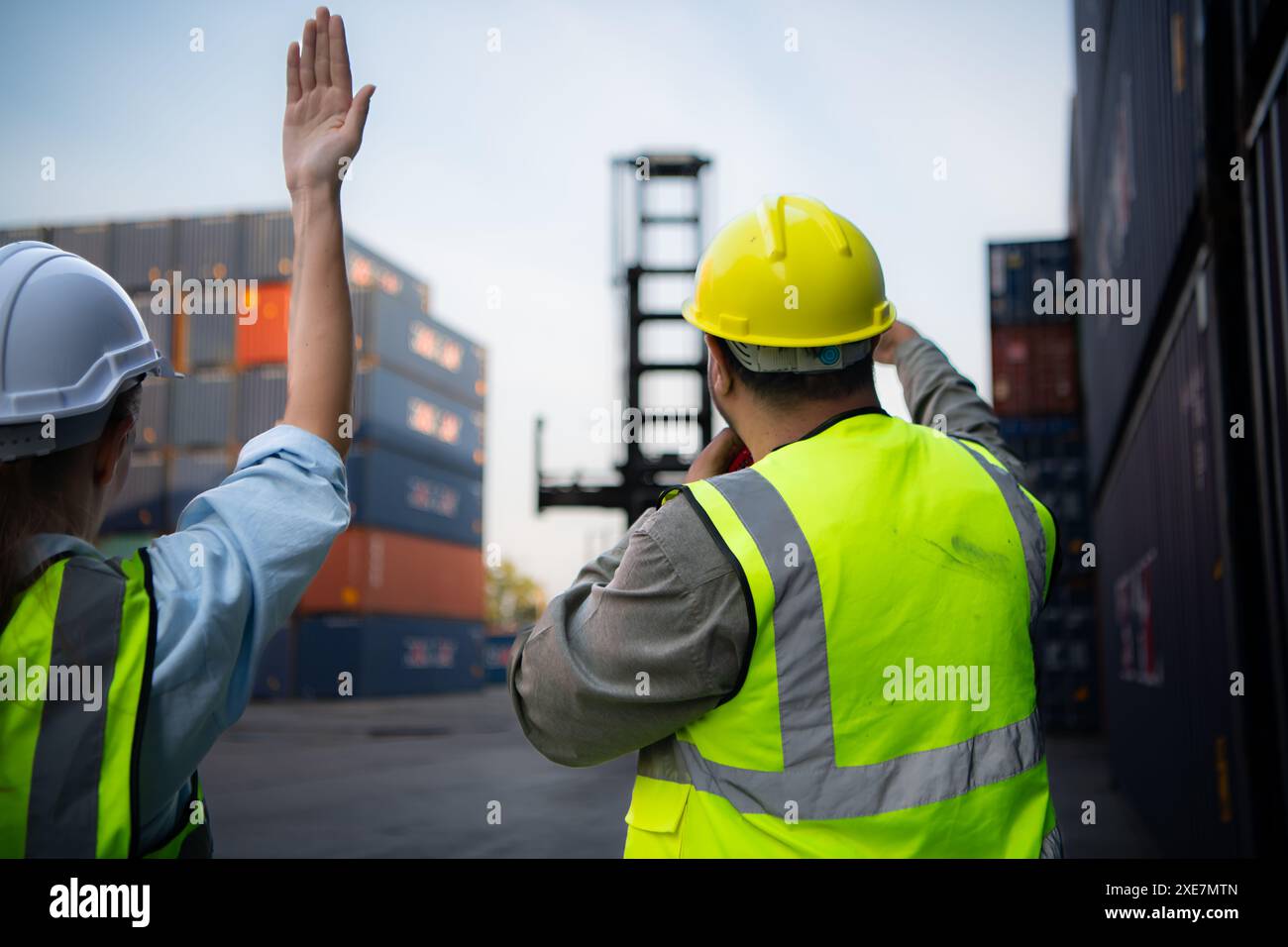 Gruppi di lavoratori del settore delle importazioni e delle esportazioni utilizzano walkie talkie per comunicare con i conducenti dei contenitori impilabili REACH Foto Stock