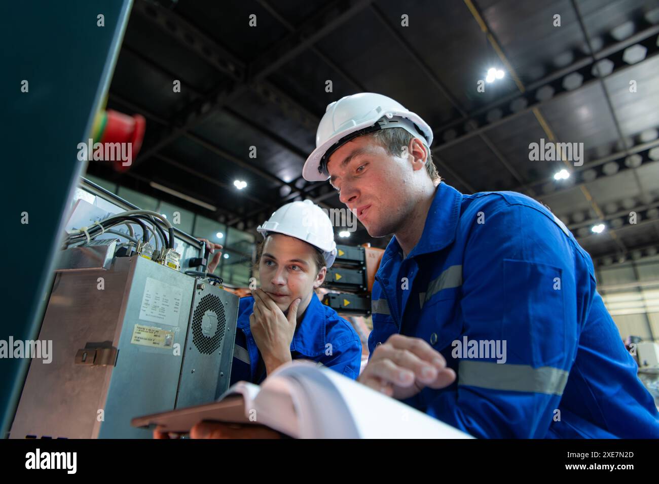 Tecnico che lavora sull'armadio di controllo elettrico del braccio robotizzato, ambiente industriale dei bracci robotici Foto Stock