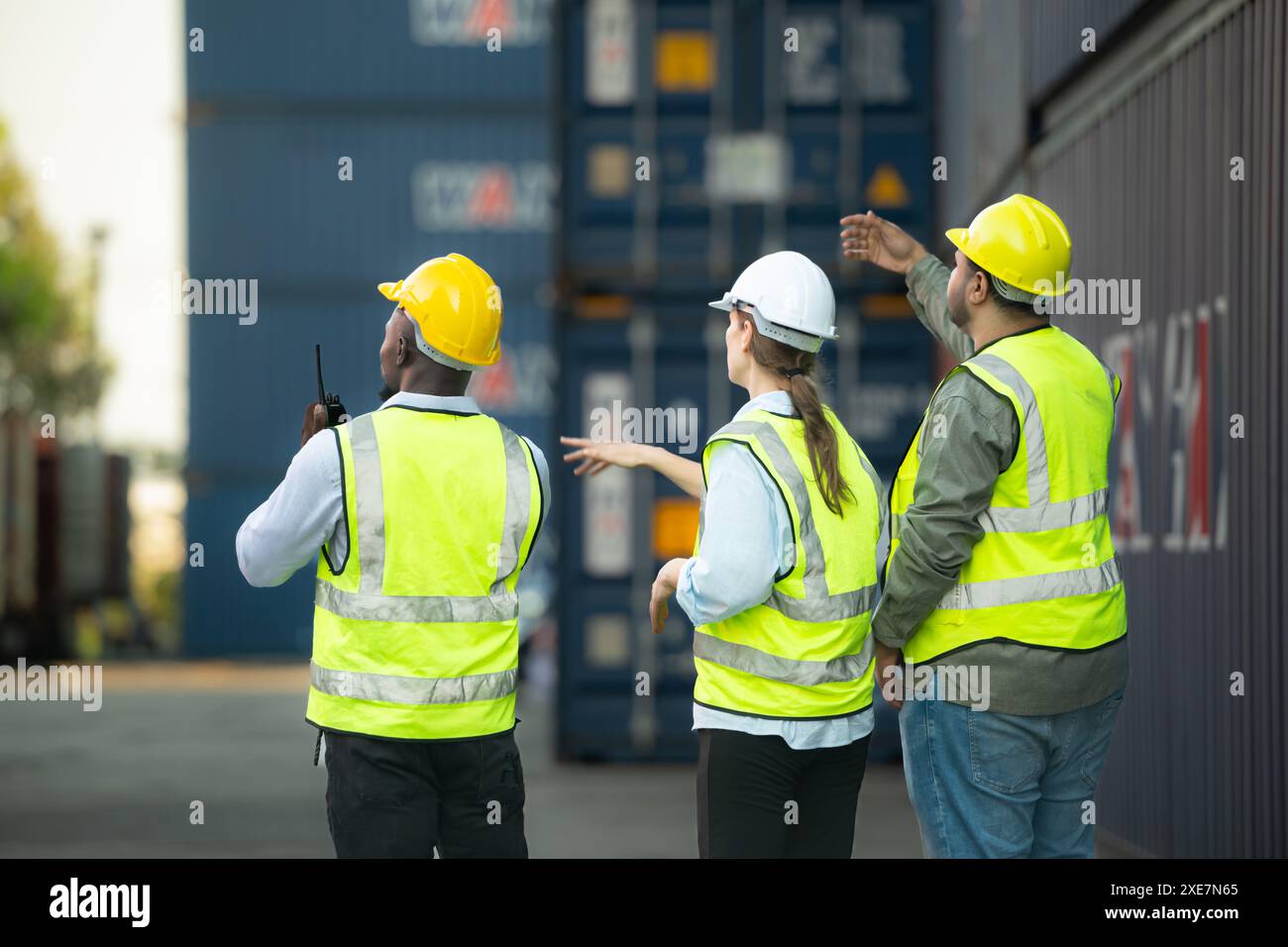 Gruppi di lavoratori del settore delle importazioni e delle esportazioni utilizzano walkie talkie per comunicare con i conducenti dei contenitori impilabili REACH Foto Stock
