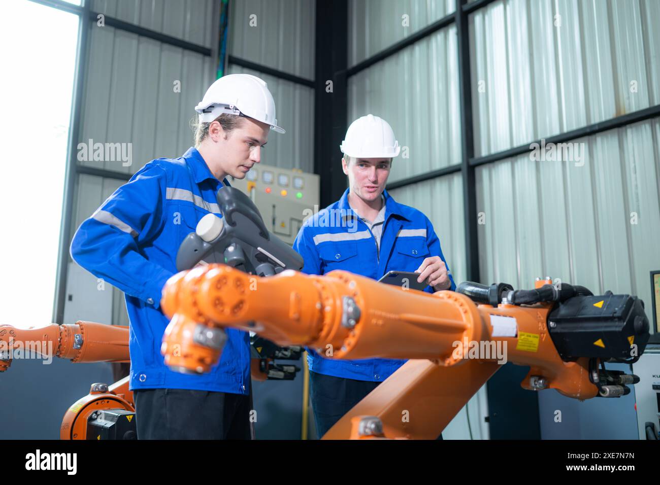 Ingegnere e tecnico che lavora con il braccio robot in fabbrica. Concetto di industria e ingegneria. Foto Stock