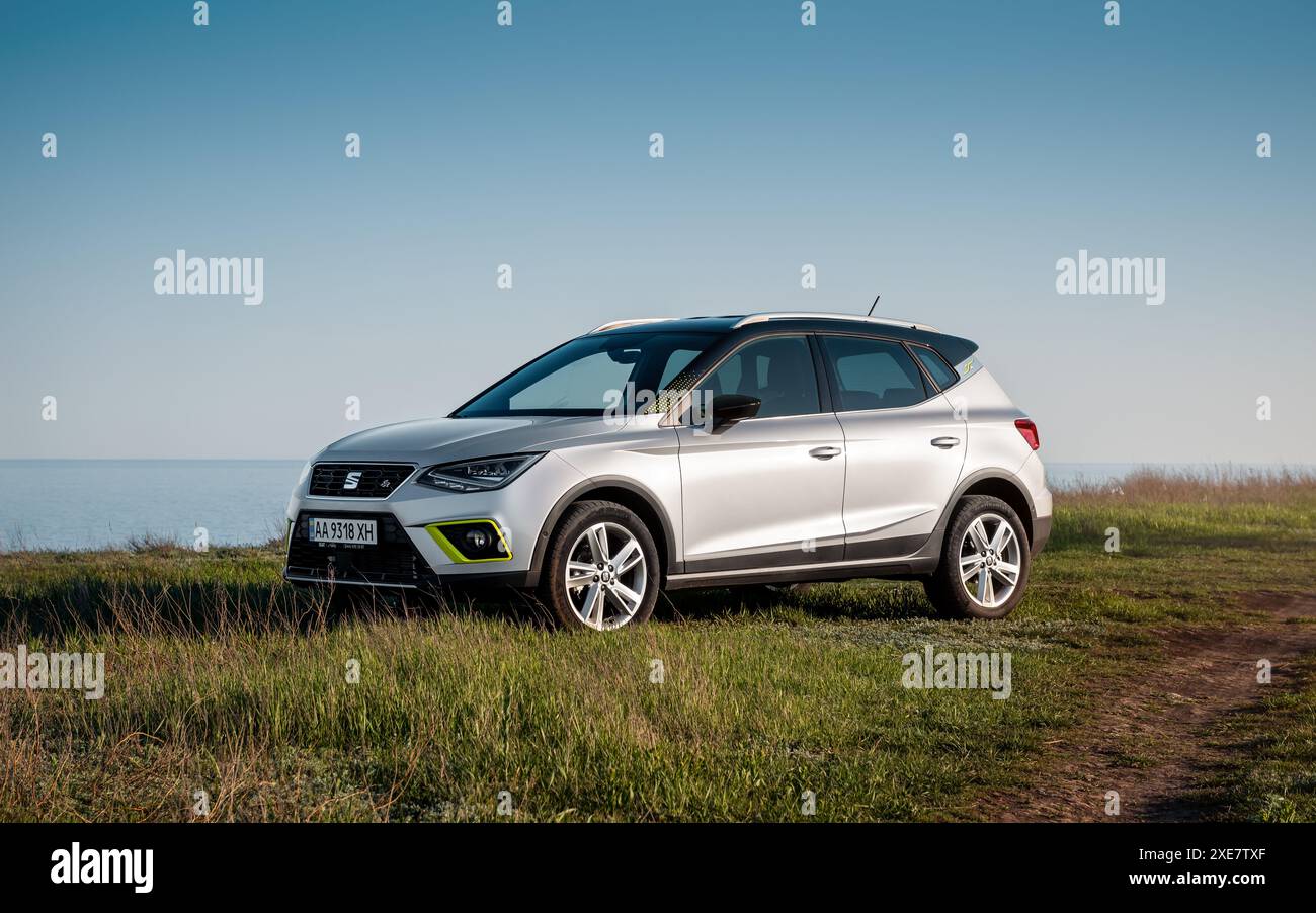 IL SEDILE Arona, parcheggiato su un'erba su un lato di strada sterrata vicino al mare. Vista frontale di tre quarti del crossover in berlina spagnola. Foto Stock