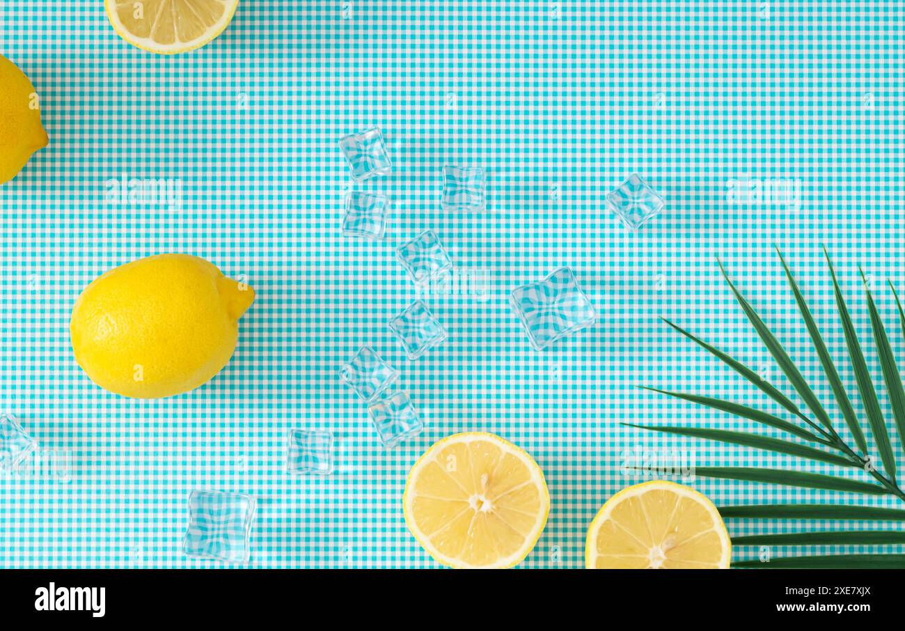 Layout creativo estivo con limoni, cubetti di ghiaccio e foglie di palma verde tropicale su sfondo bianco e blu. Concetto di frutta estiva minimalista. Foto Stock