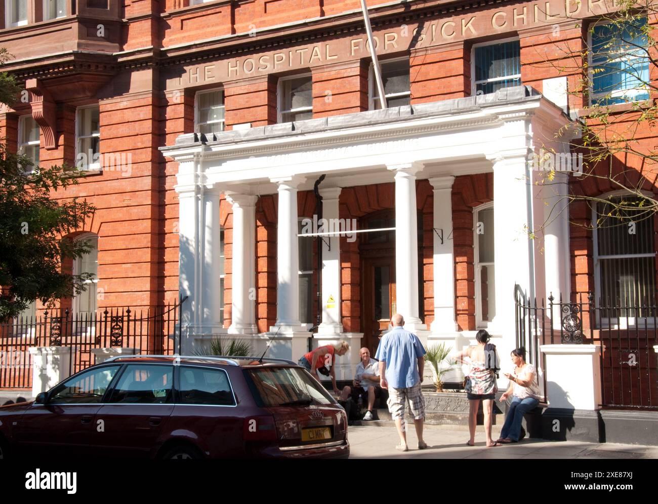 Ingresso al Great Ormond Street Hospital for Sick Children - il primo ospedale per bambini costruito in Gran Bretagna, persone sedute e chiacchierate all'esterno Foto Stock