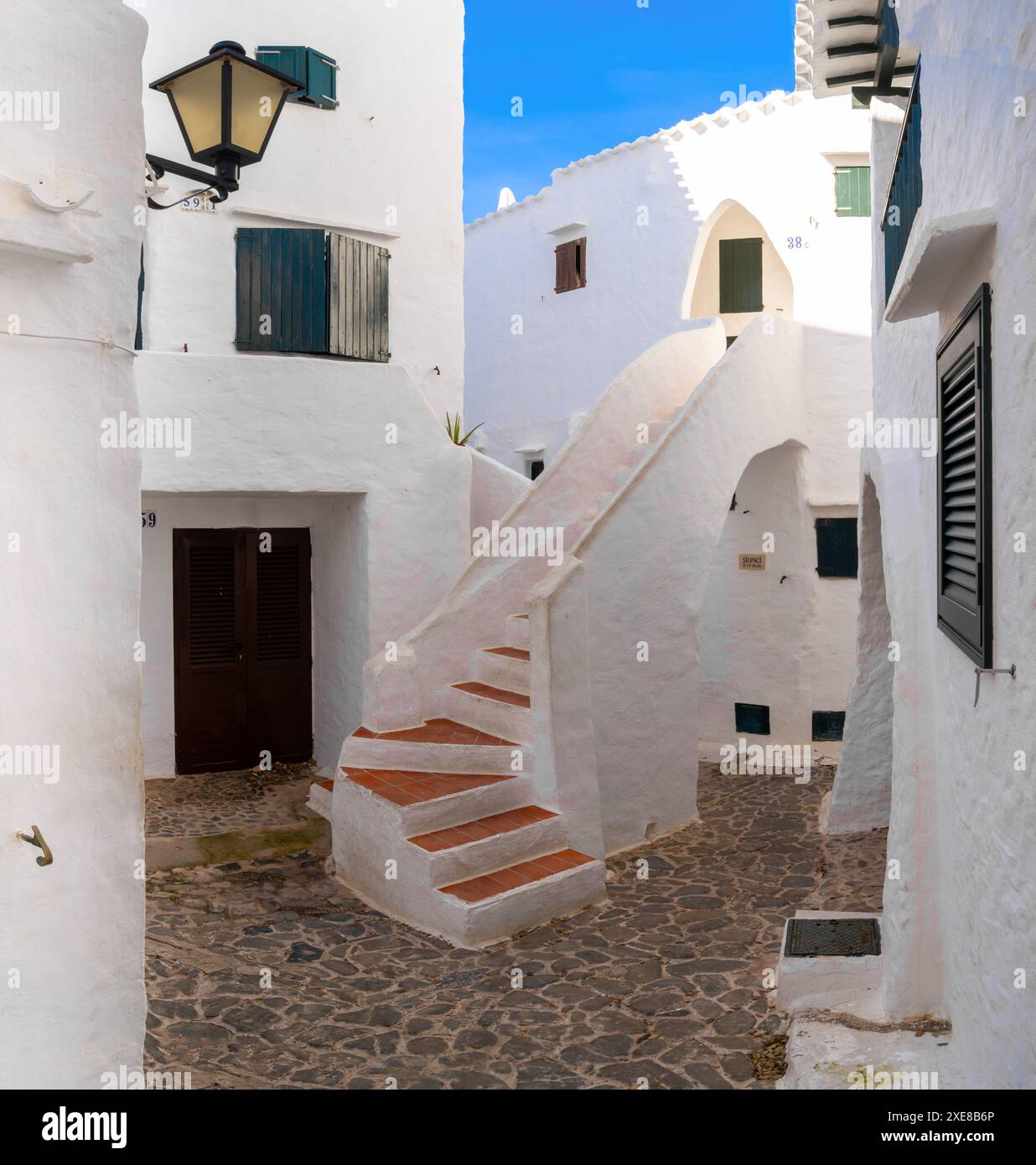 Cortile con case bianche e scale nel centro del villaggio di Binibeca Vell Foto Stock