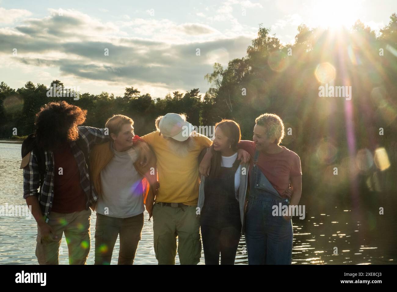 Amici intimi che si godono il tramonto sul lago Foto Stock