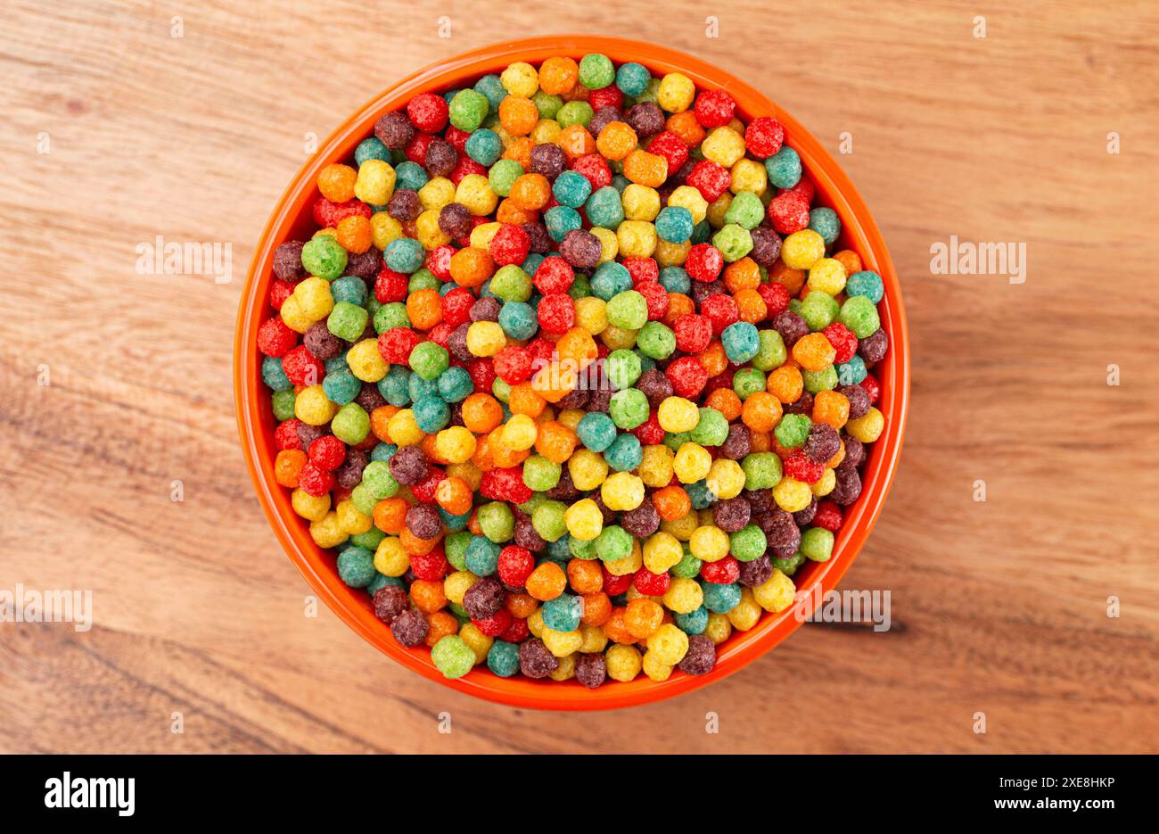 Una ciotola di piccoli cereali aromatizzati alla frutta su un tavolo da cucina in legno Foto Stock