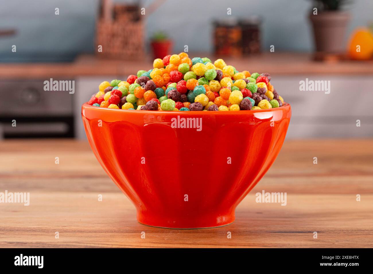 Una ciotola di piccoli cereali aromatizzati alla frutta su un tavolo da cucina in legno Foto Stock