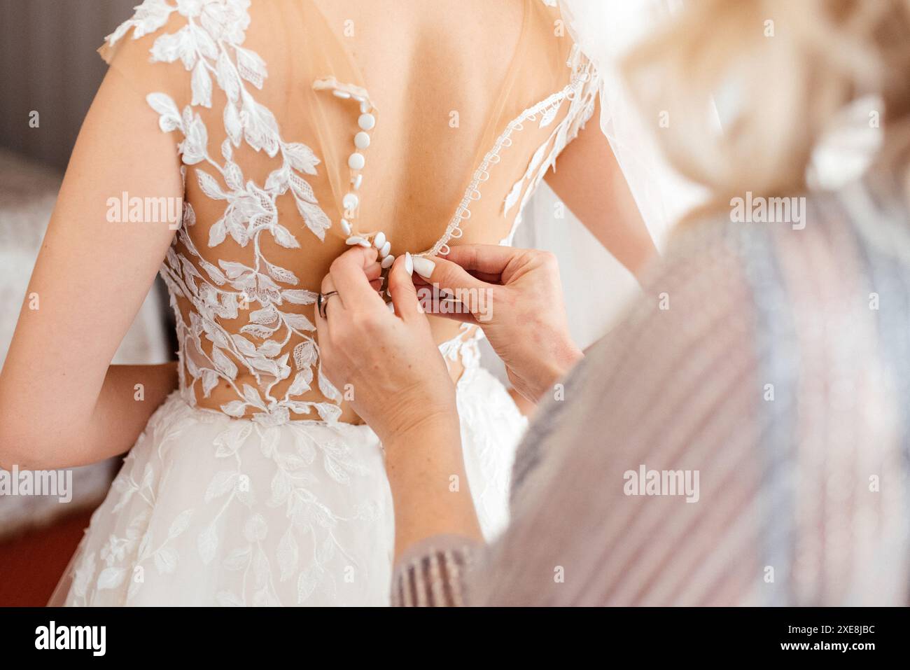 Madre che aiuta la sposa con abito da sposa, preparazione per il giorno di nozze prima della cerimonia Foto Stock