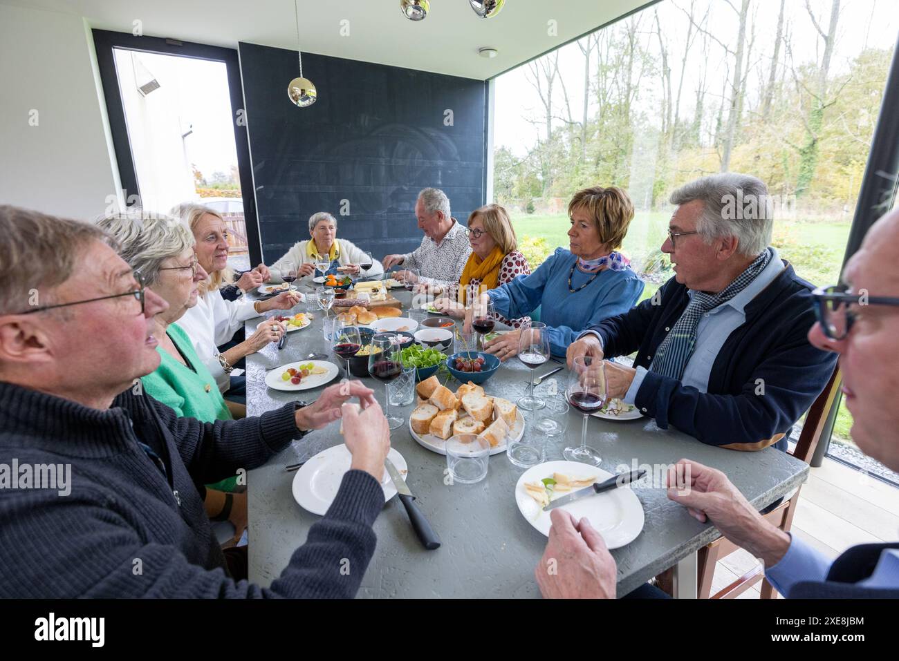 Riunione di famiglia per un pasto in una luminosa sala da pranzo Foto Stock