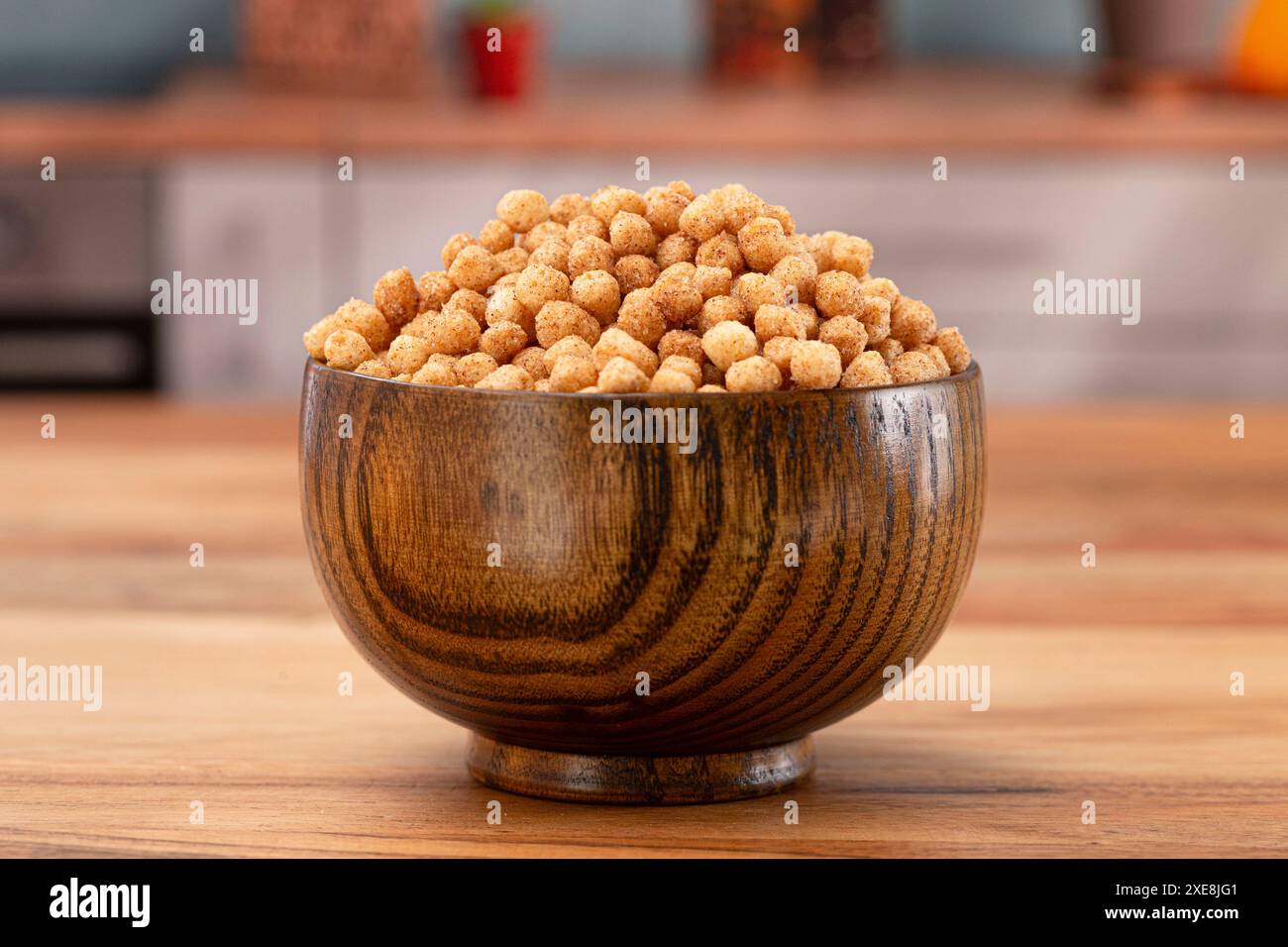 Ciotola di piccolo pane tostato alla cannella a forma di palla e cereali da colazione su un tavolo da cucina in legno Foto Stock