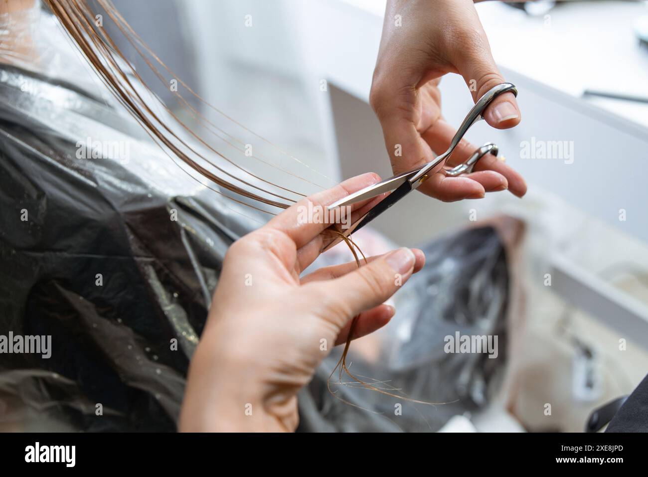 Il parrucchiere taglia i capelli di una giovane donna bionda nel parrucchiere Foto Stock