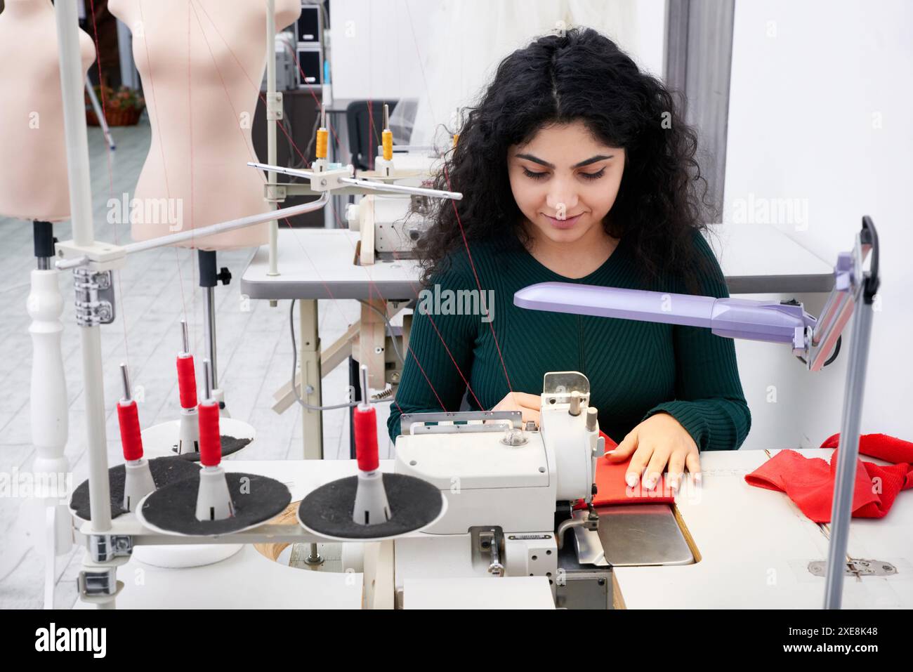 Sarta che utilizza una macchina da cucire overlock professionale in officina. Attrezzature per bordare, orlare o cucire vestiti a ta Foto Stock