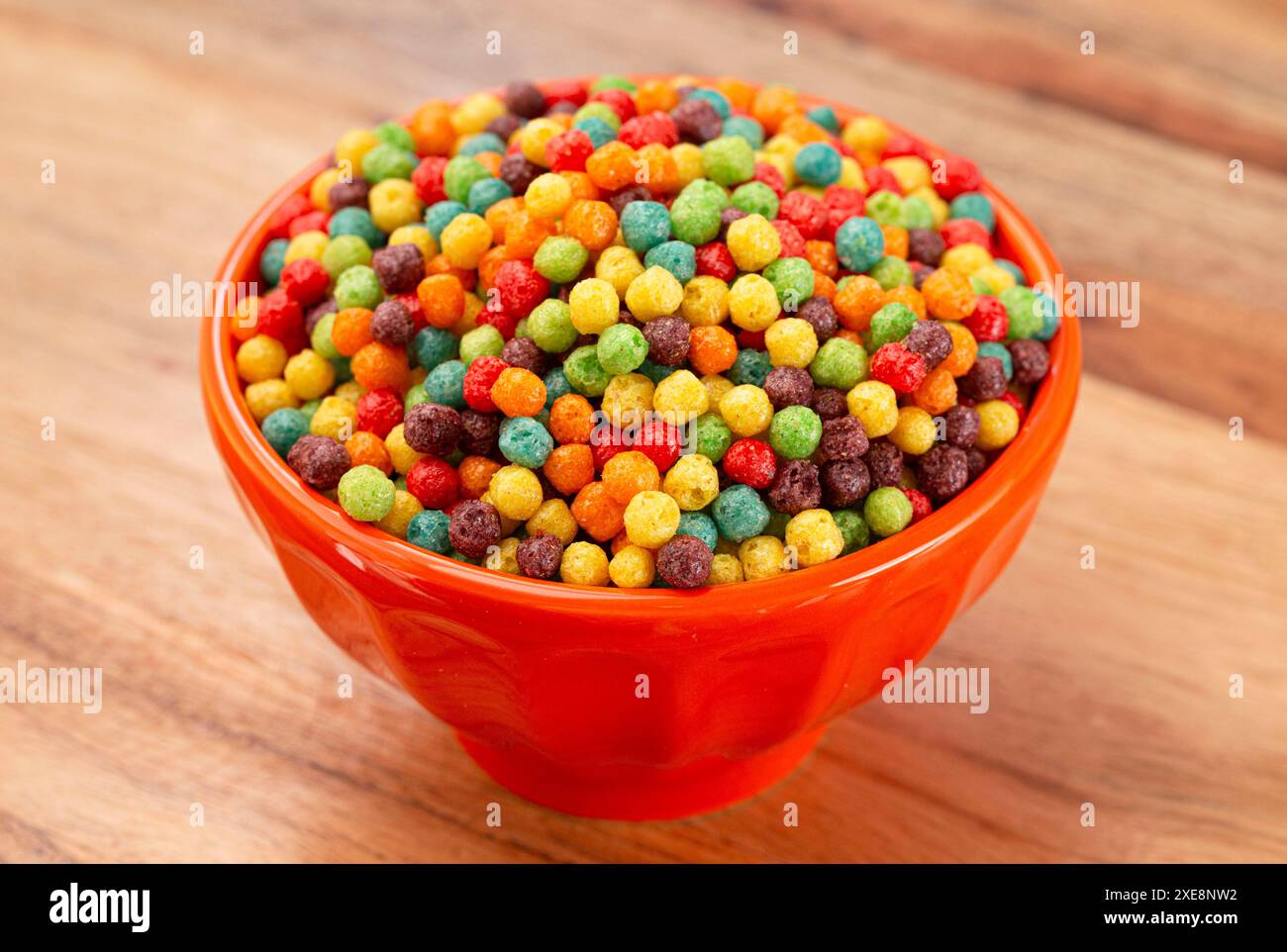 Una ciotola di piccoli cereali aromatizzati alla frutta su un tavolo da cucina in legno Foto Stock