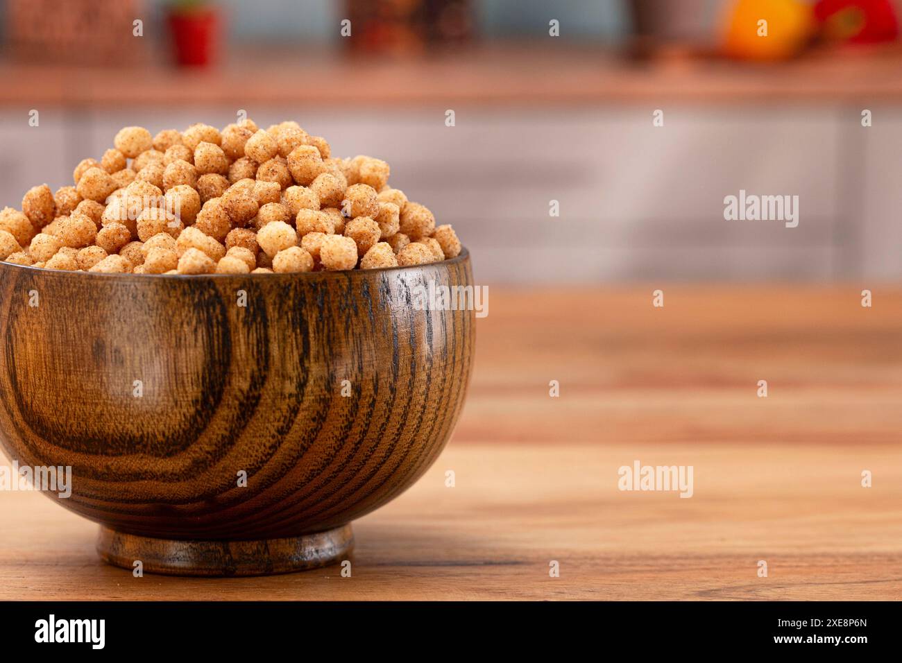 Ciotola di piccolo pane tostato alla cannella a forma di palla e cereali da colazione su un tavolo da cucina in legno Foto Stock
