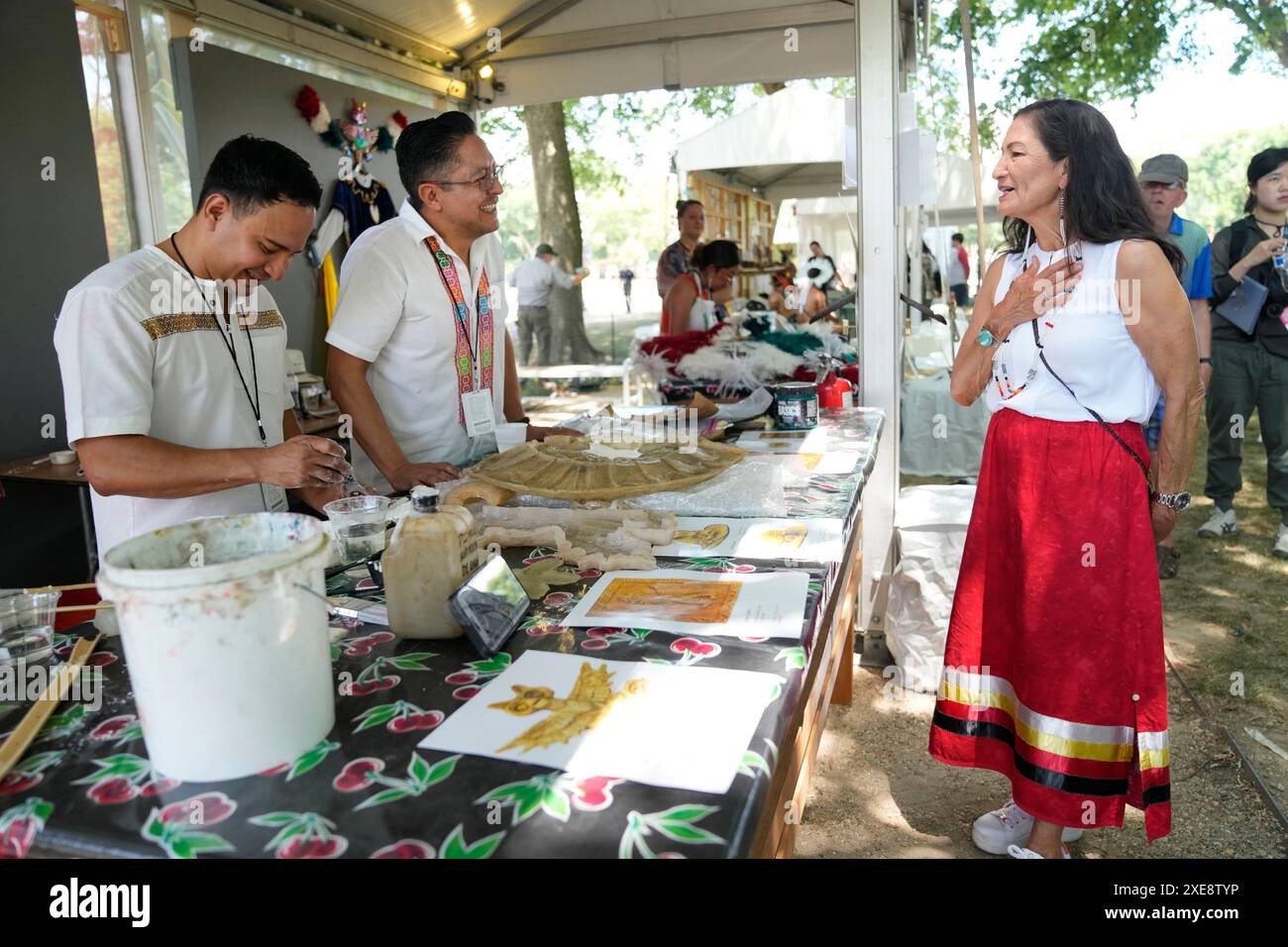Interior Secretary Deb Haaland, right, visits a plaster art booth on opening day of the Smithsonian Folklife Festival, Wednesday, June 26, 2024, on the National Mall in Washington. This year's festival theme is "Indigenous Voices of the Americas" and will run through July 1. (AP Photo/Jacquelyn Martin) Foto Stock