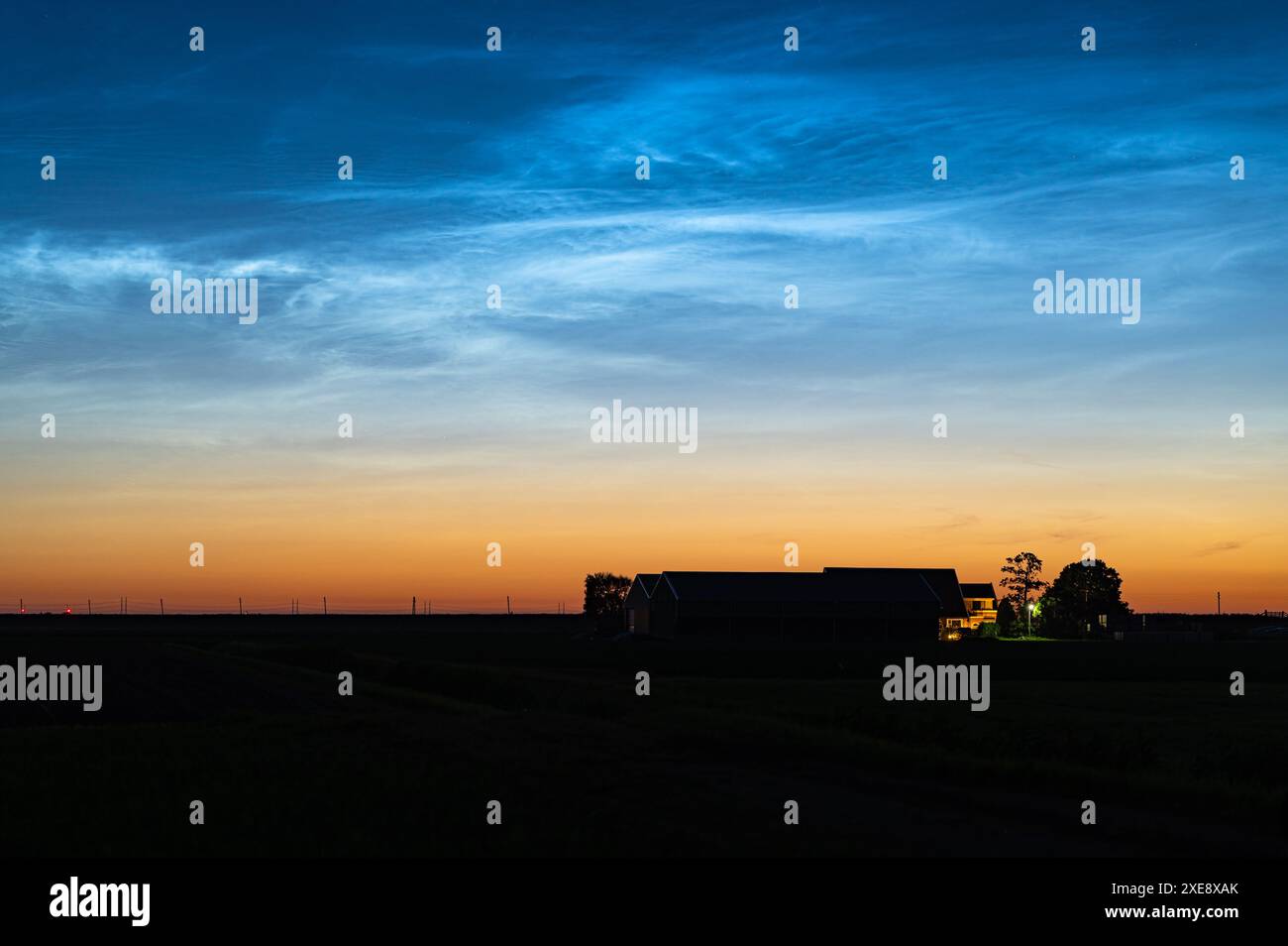 Vista panoramica di nuvole nocciolenti o NLC sopra una fattoria durante il periodo delle notti più brevi di giugno Foto Stock