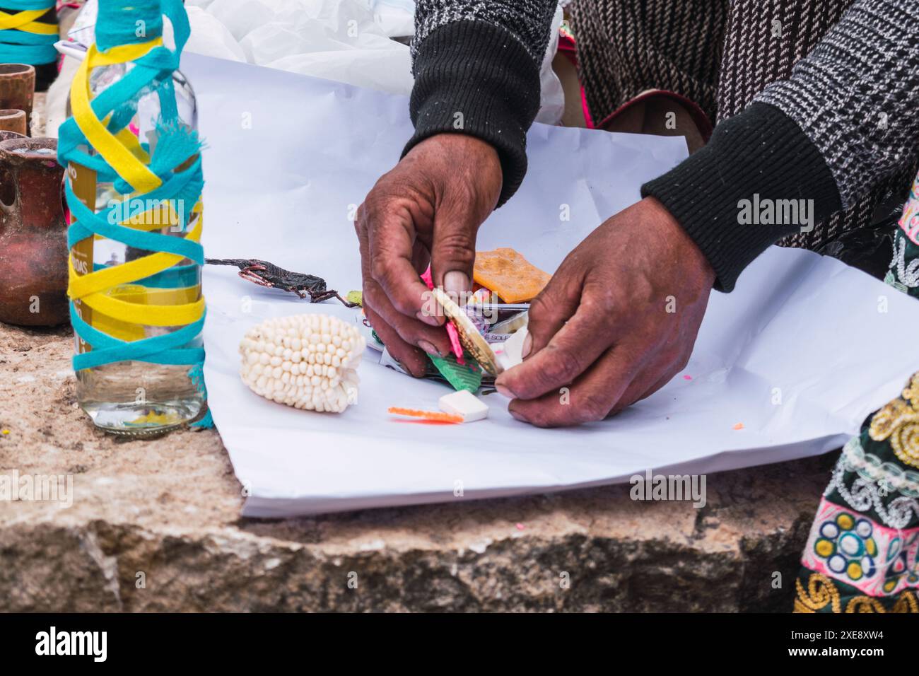 Tradizionale rituale di pagamento alla terra con foglie di coca e chicha de jora nelle Ande della catena montuosa in una giornata di sole Foto Stock