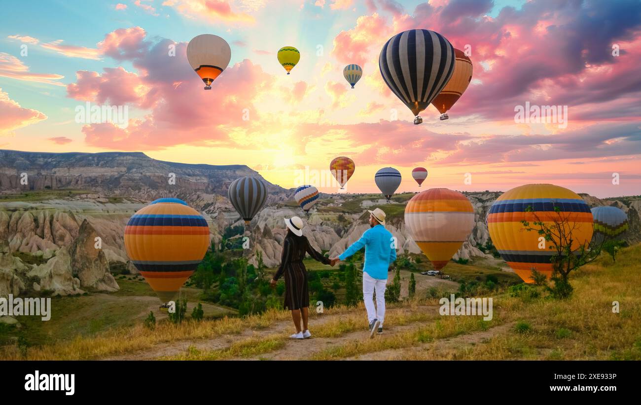 Felice giovane coppia durante l'alba guardando le mongolfiere di Kapadokya Cappadocia Turchia Foto Stock