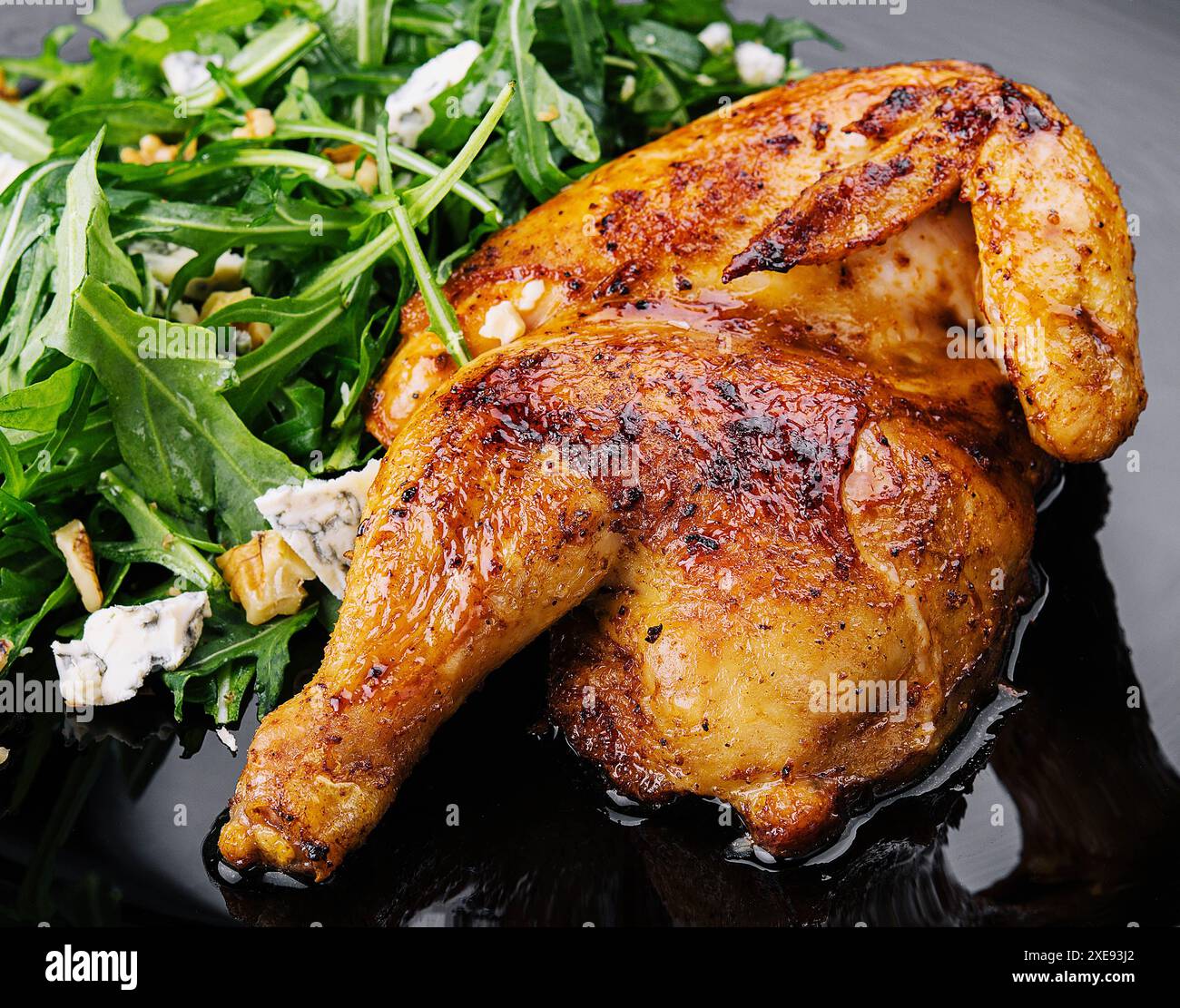 Pollo fritto con insalata di rucola su piatto nero Foto Stock