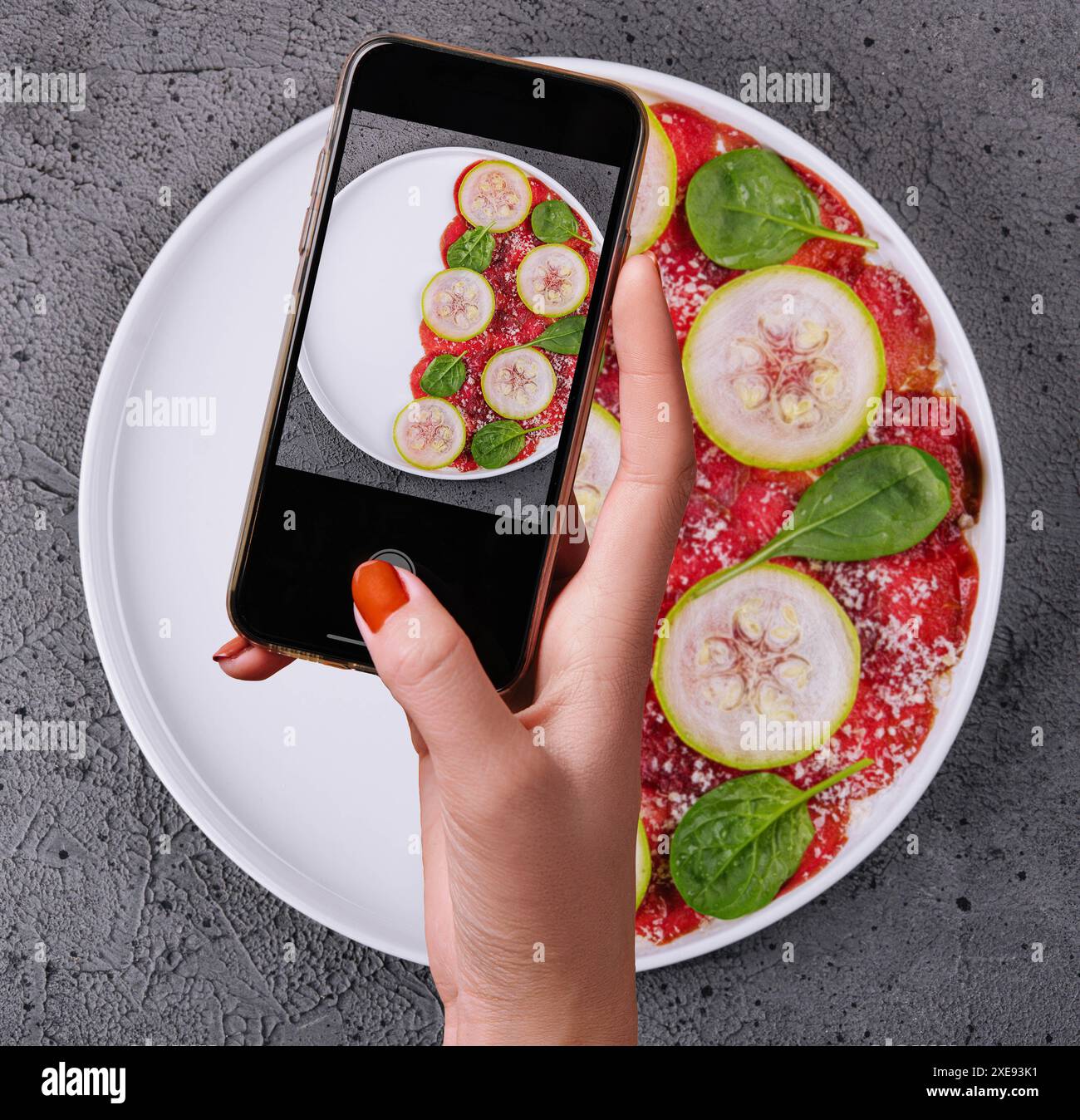 Donna che fa una foto di carpaccio di manzo italiano con zucchine a fette Foto Stock