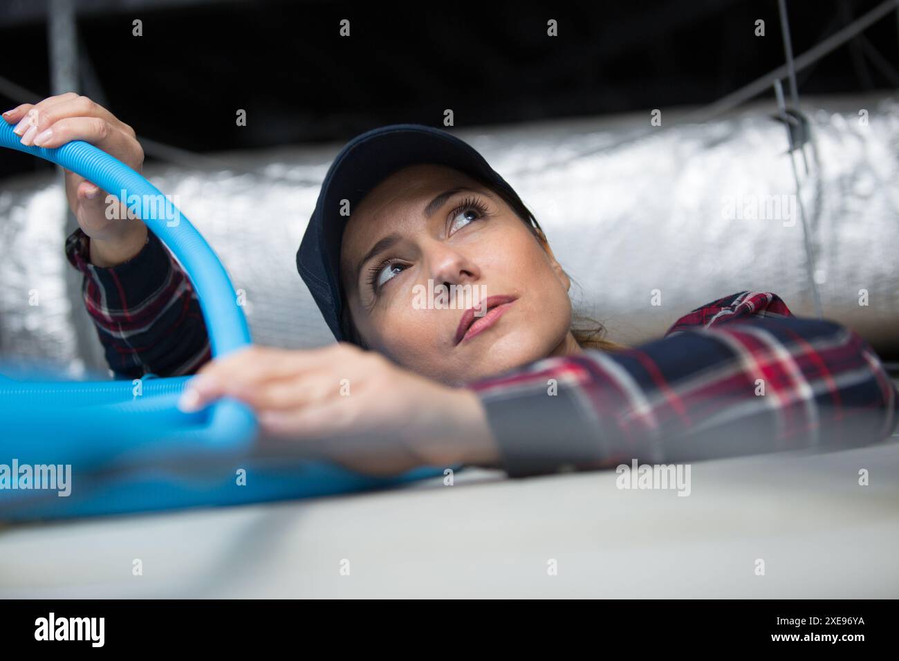 donna che inserisce tubo nel tetto Foto Stock