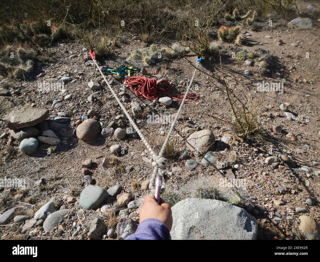 Dettaglio di una pratica di alpinismo: Persona irriconoscibile che prova l'affidabilità di un sistema di fitoancoraggio. Foto Stock