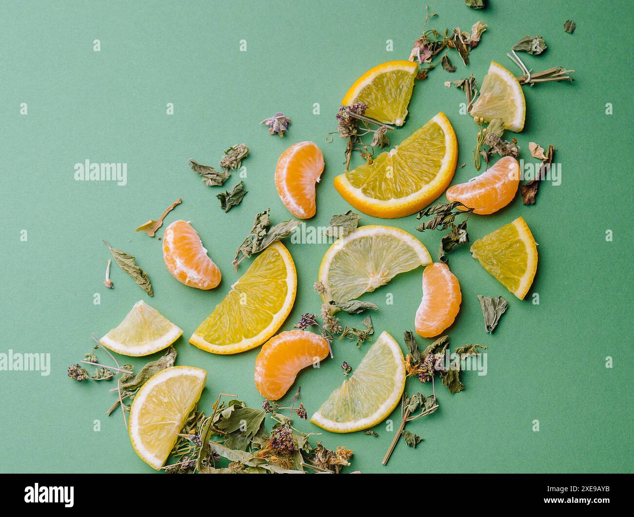 Tè in foglia con fette di arancia e mandarino su sfondo verde Foto Stock