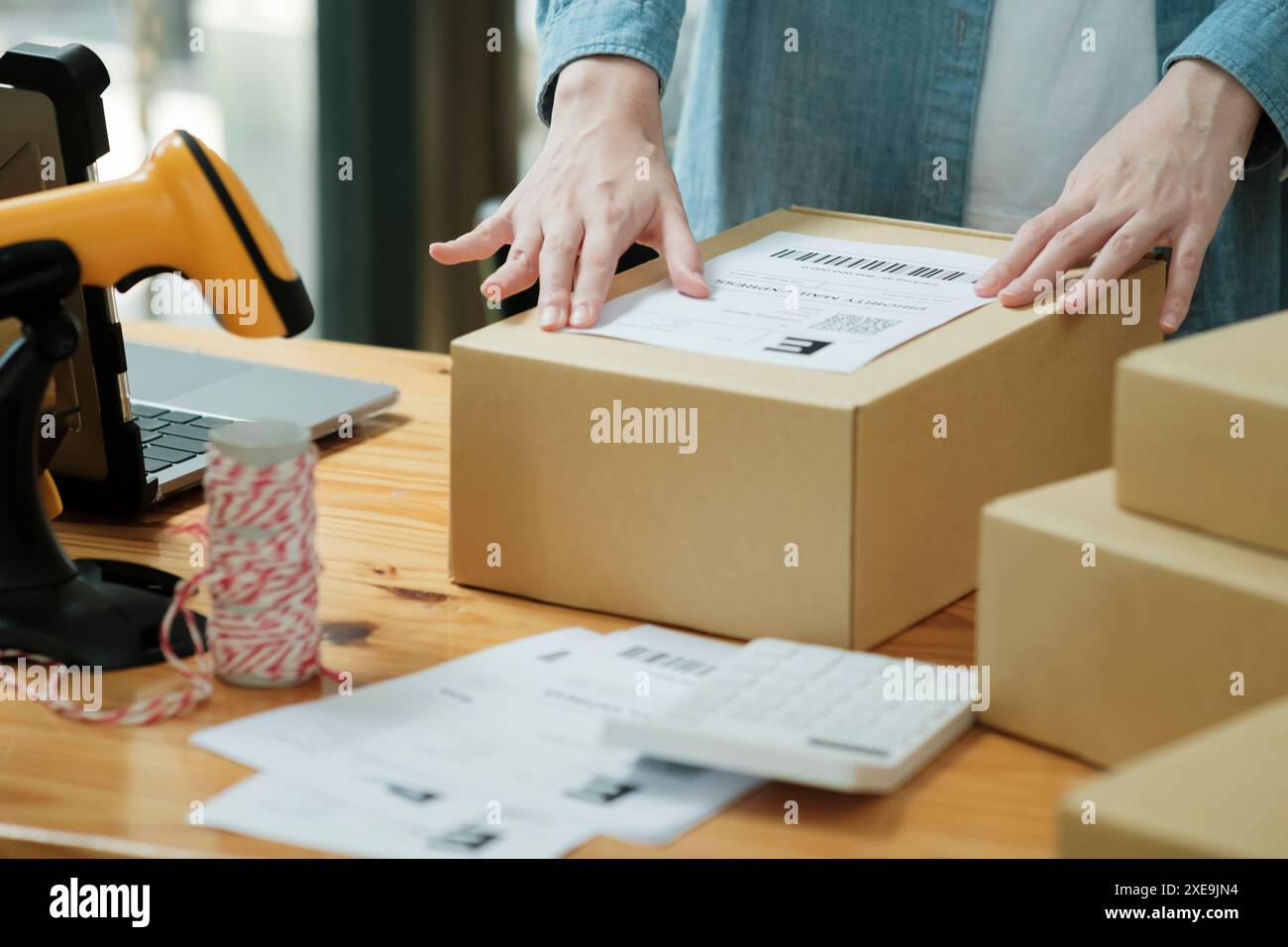 Scansione del codice a barre sulla scatola di spedizione con scanner Foto Stock