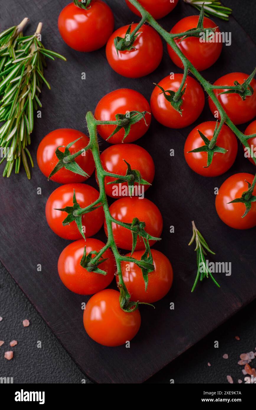 Deliziosi pomodori ciliegini freschi su un ramoscello con spezie ed erbe aromatiche Foto Stock