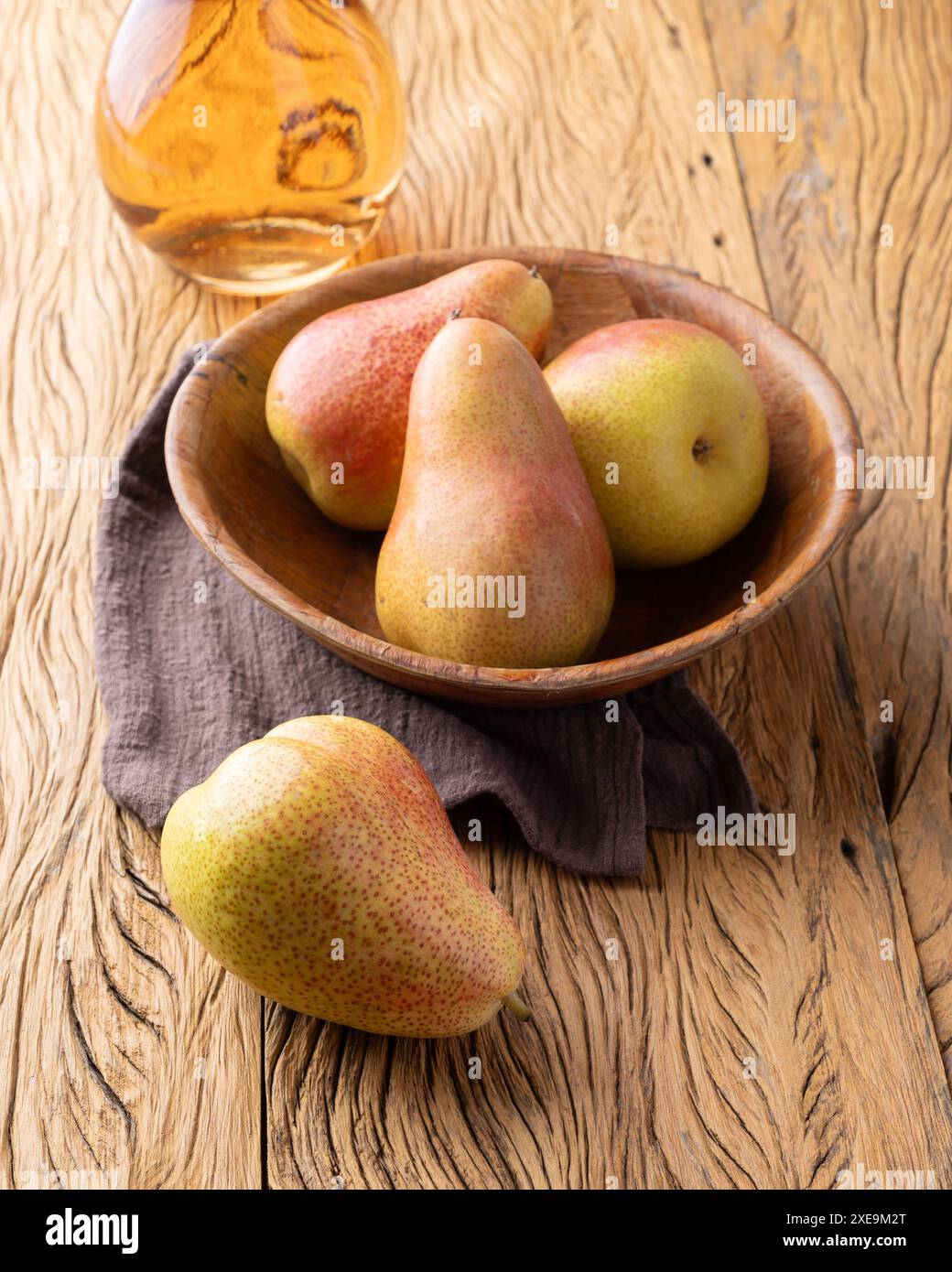 Pere rosse in una ciotola con vino rosa su un tavolo di legno. Foto Stock