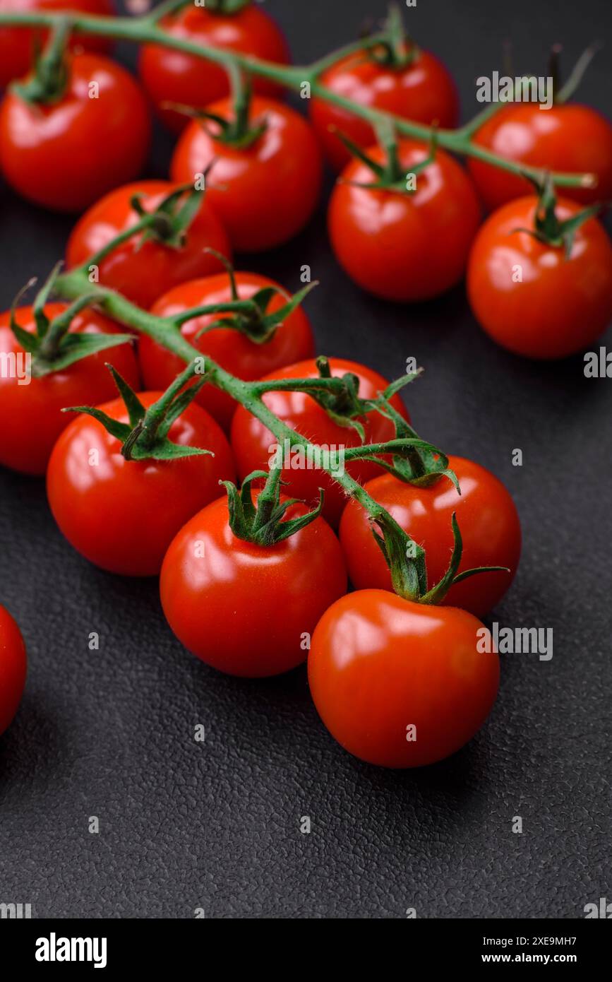 Deliziosi pomodori ciliegini freschi su un ramoscello con spezie ed erbe aromatiche Foto Stock