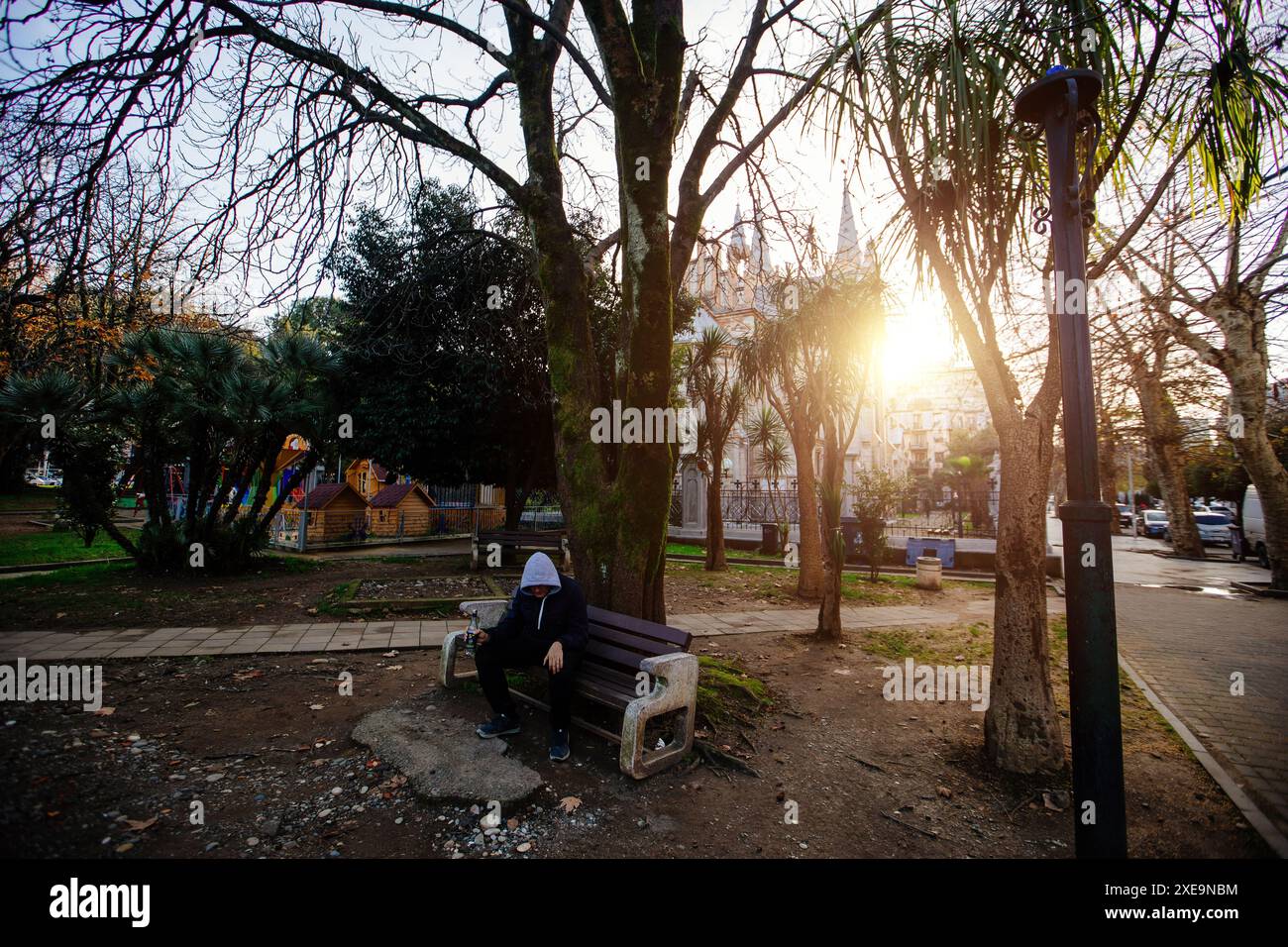 Senzatetto o alcolico che dorme sulla panca. Povero uomo sulla strada cittadina. Foto Stock