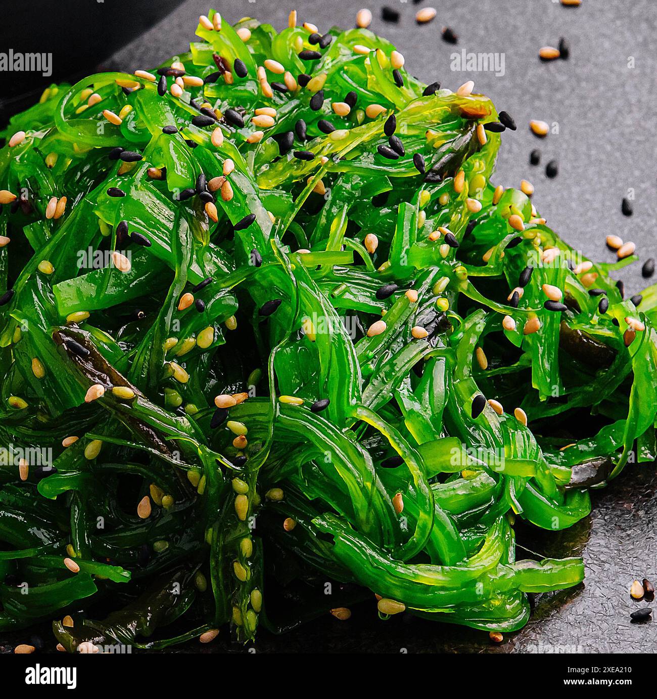 Insalata di alghe wakame con semi di sesamo su piatto nero Foto Stock