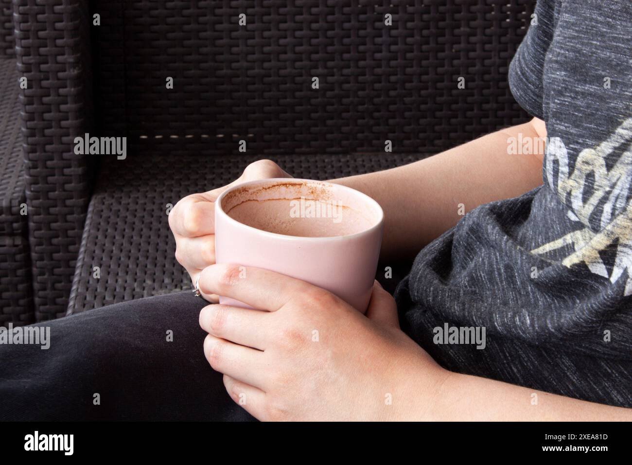 Caffè caldo in una tazza. Una donna che tiene in mano una tazza. Atmosfera intima. Le mani di una donna tengono il caffè. Foto Stock