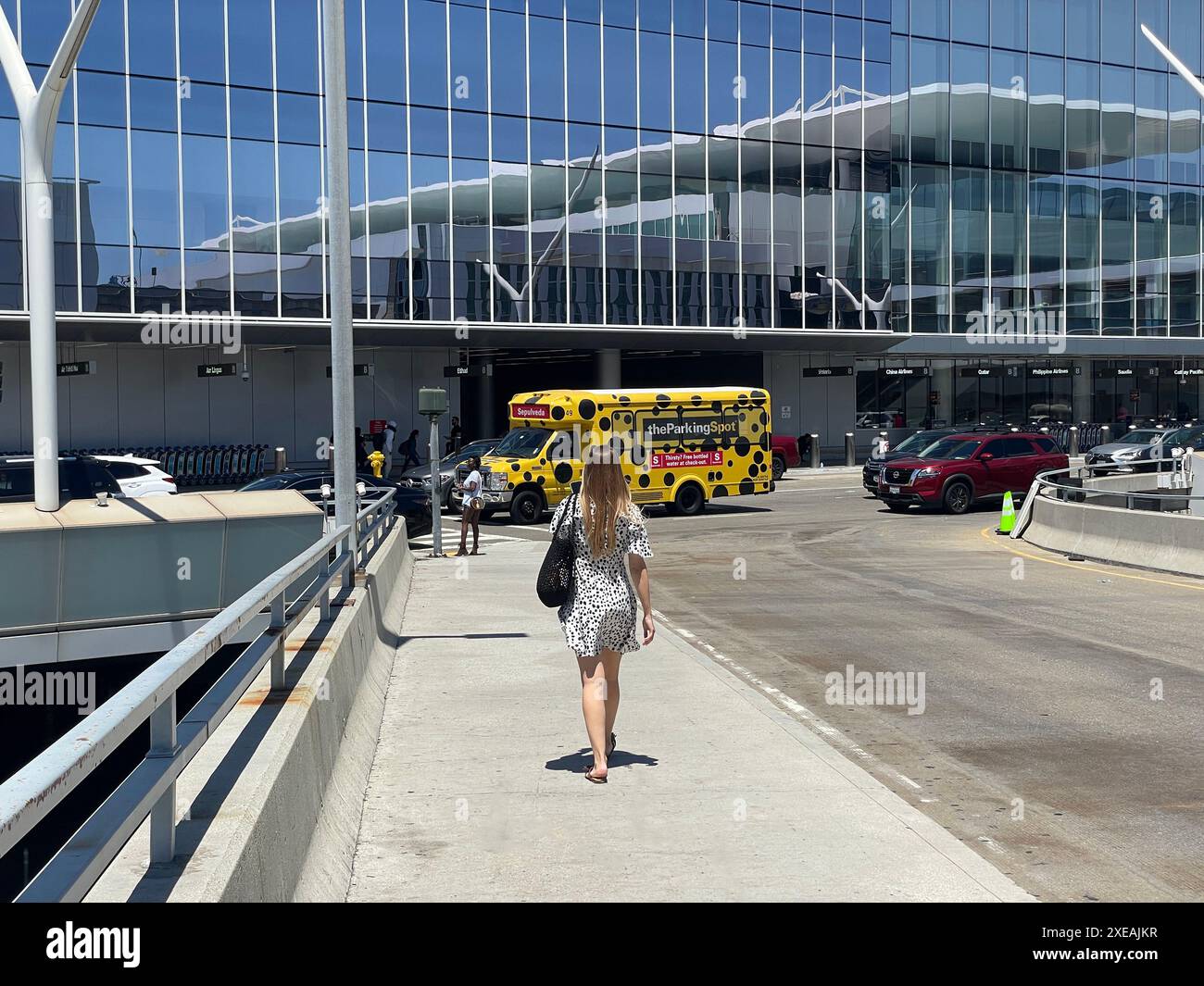 Piano di partenza del terminal internazionale Tom Bradley con edificio riflesso nella finestra e autobus navetta a pois per il parcheggio a Los Angeles, California, Stati Uniti Foto Stock