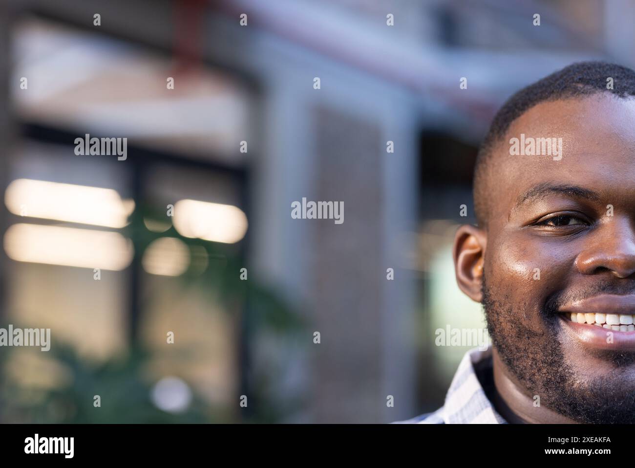 Uomo sorridente in un informale abbigliamento da lavoro in un moderno ambiente da ufficio Foto Stock