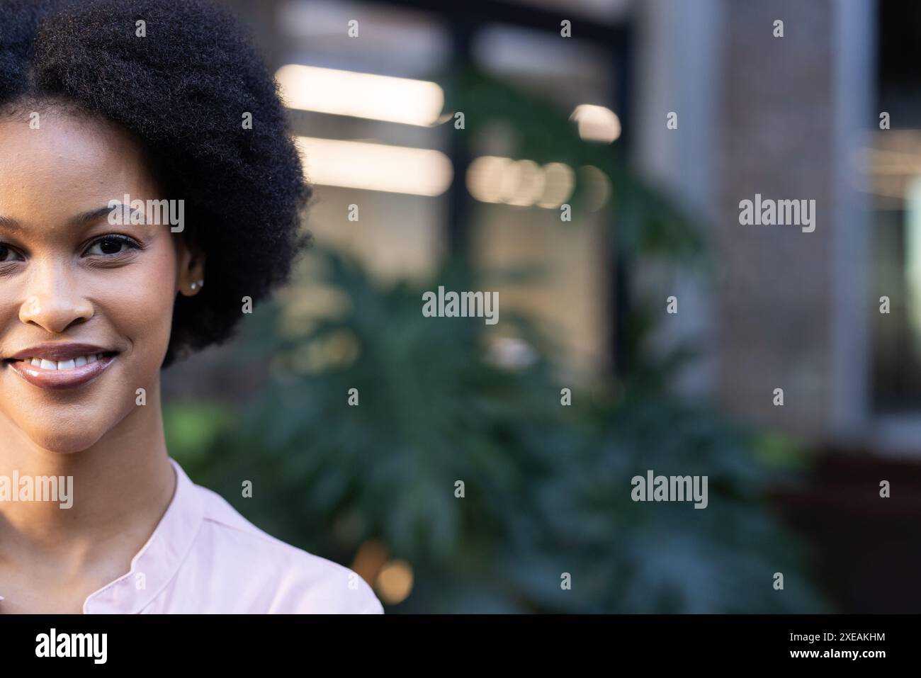 Donna d'affari afro-americana sorridente in un ambiente d'ufficio con un abbigliamento casual Foto Stock