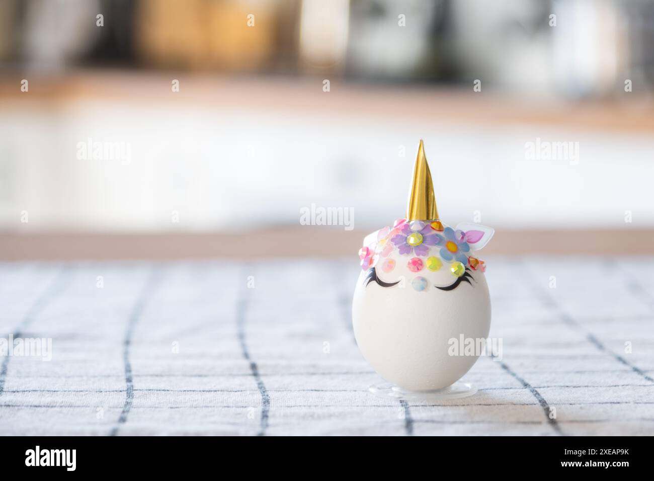 Artigianato pasquale - decora un uovo a forma di unicorno con strass, corno, fiori all'interno di una casa Foto Stock