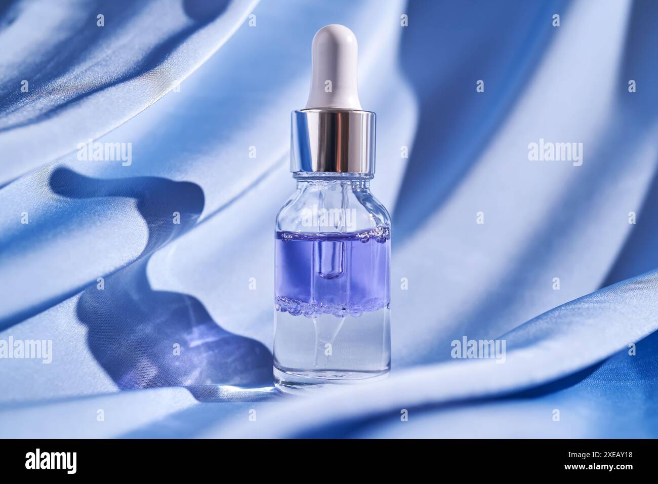 Siero facciale bicomponente su fondo di seta blu. Foto Stock