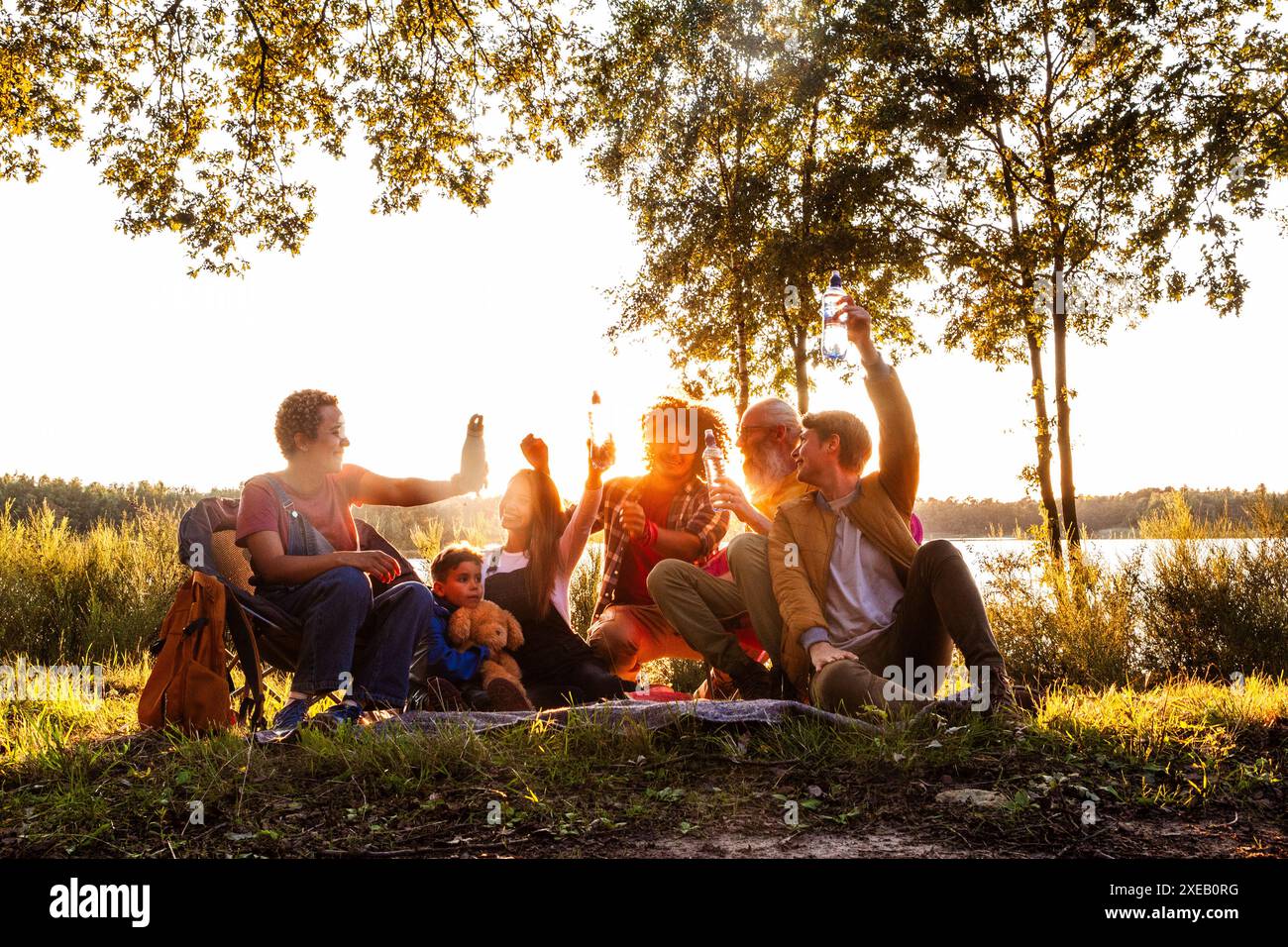 Riunione dell'ora d'oro, amici e famiglia rilassati sul lago Foto Stock