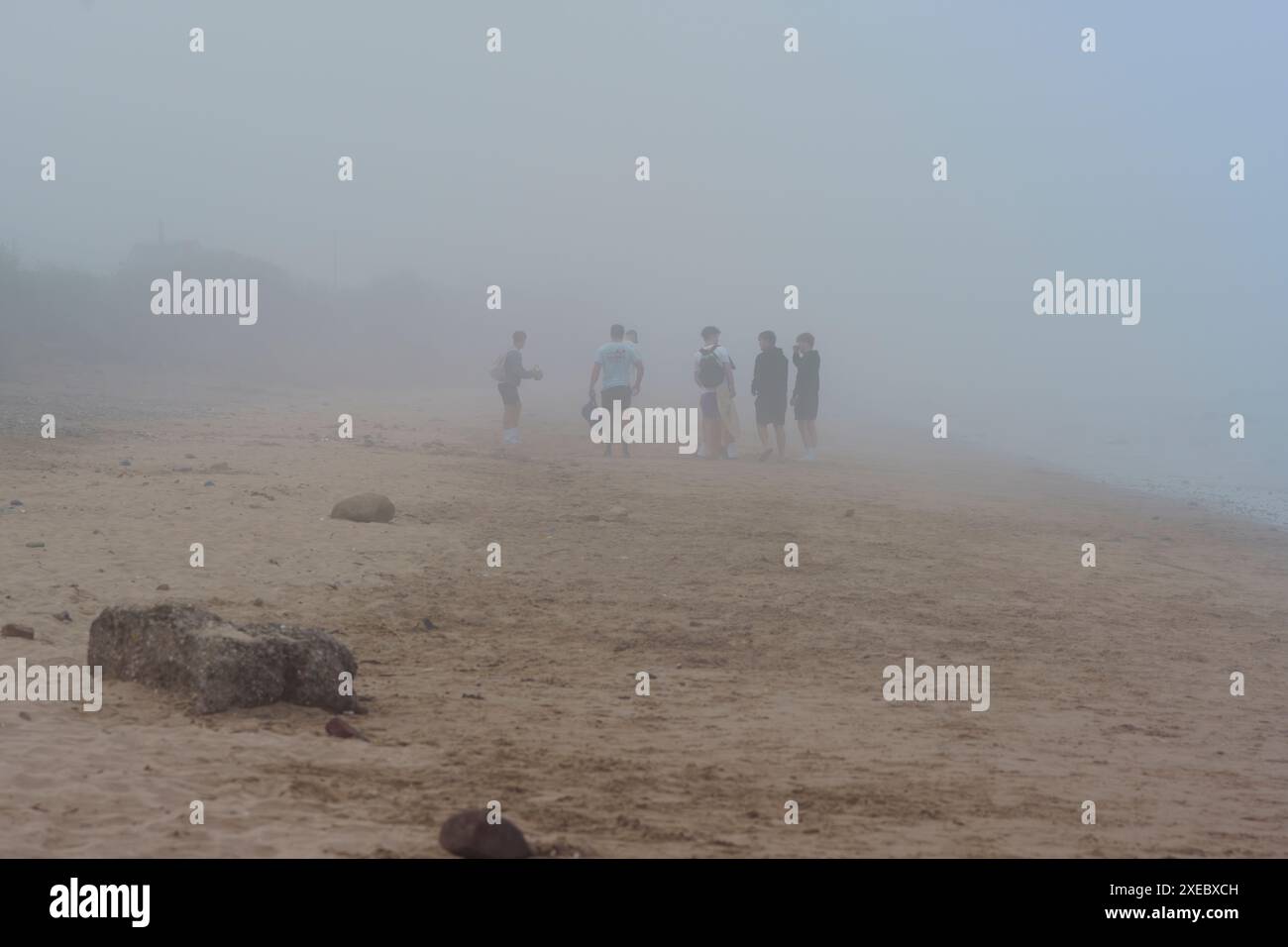 Un gruppo di giovani amici maschi bianchi si divertono a fare una passeggiata lungo la spiaggia di Fraisthorpe, nel tardo pomeriggio in una nebbia estiva. Costa dello Yorkshire orientale Foto Stock