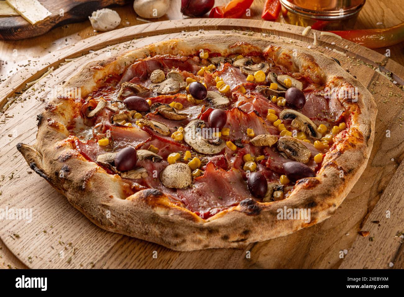Pizza capriciosa, pizza classica con prosciutto, funghi, mais e olive su tavola di legno. Pizza italiana tradizionale. Foto Stock
