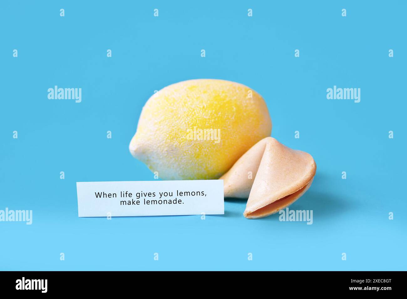 Biscotto della fortuna con testo motivazionale su carta che dice "quando la vita ti dà limoni, fai limonata" su sfondo blu Foto Stock