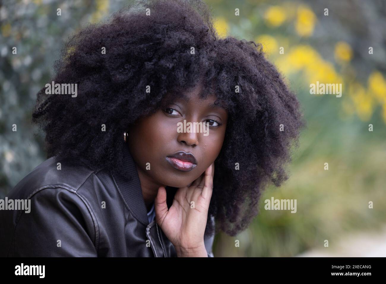 Premurosa donna afroamericana con elegante afro in un ambiente autunnale Foto Stock