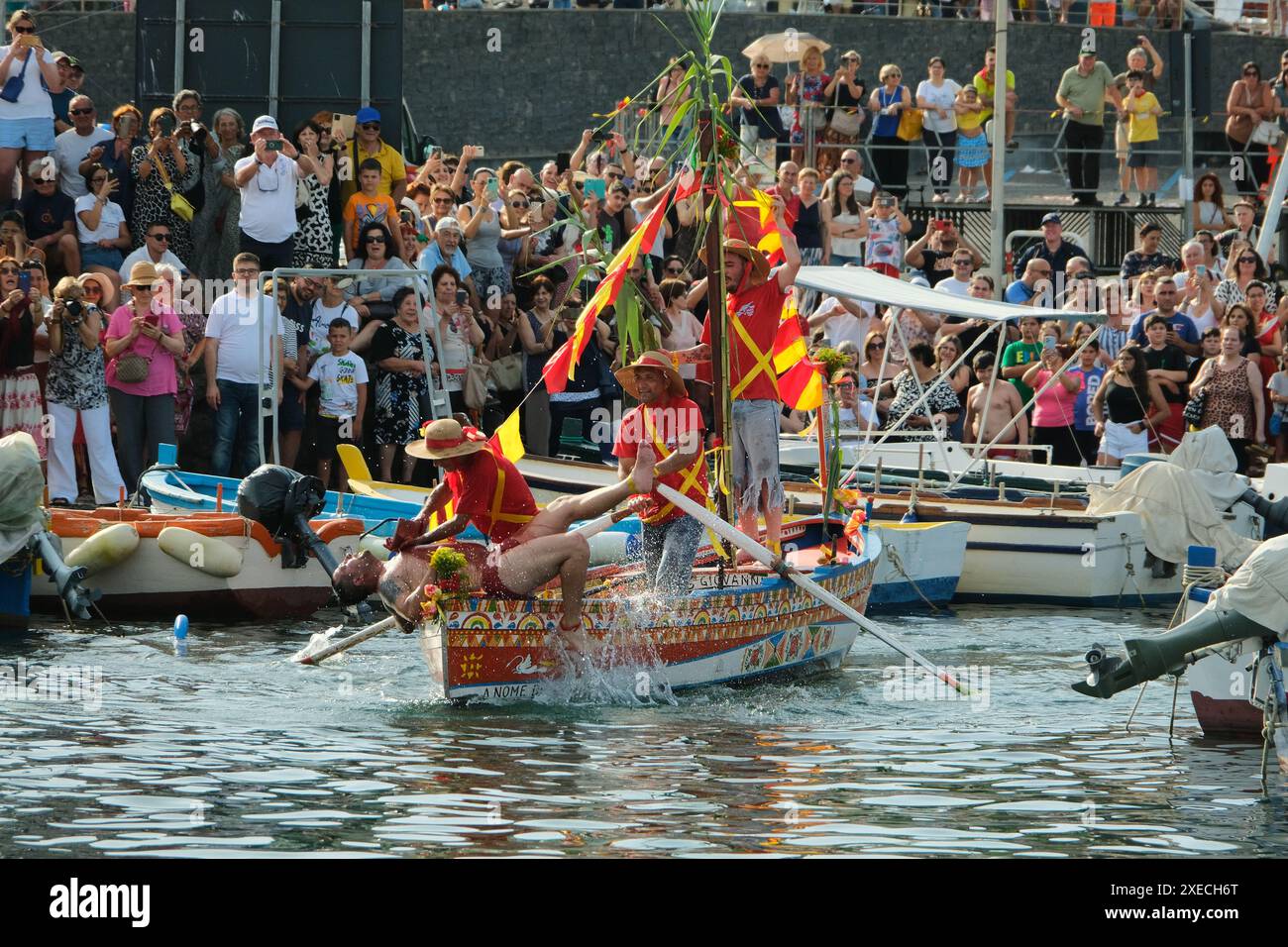 ACI TREZZA, ITALIA - 24 GIUGNO 2024 - Festa tradizionale di San Giovanni. Sfilata tradizionale di San Giovanni con pisci a mari dove riproducono la caccia al tonno. Il tonno viene derubato da un giovane che finalmente riesce a fuggire dai pescatori Foto Stock