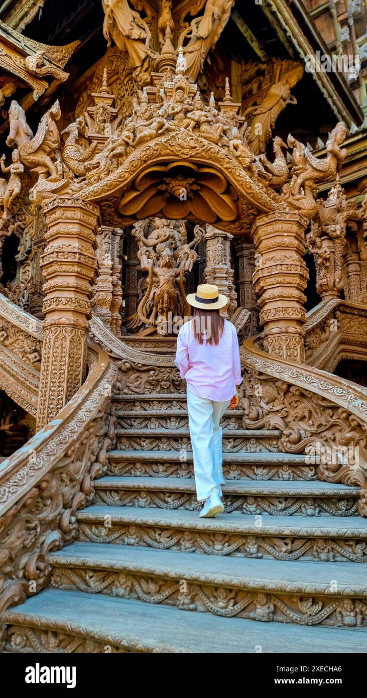 Una donna misteriosa in un cappello di paglia scende con grazia una scala con uno scopo, incarnando eleganza e avventura Foto Stock