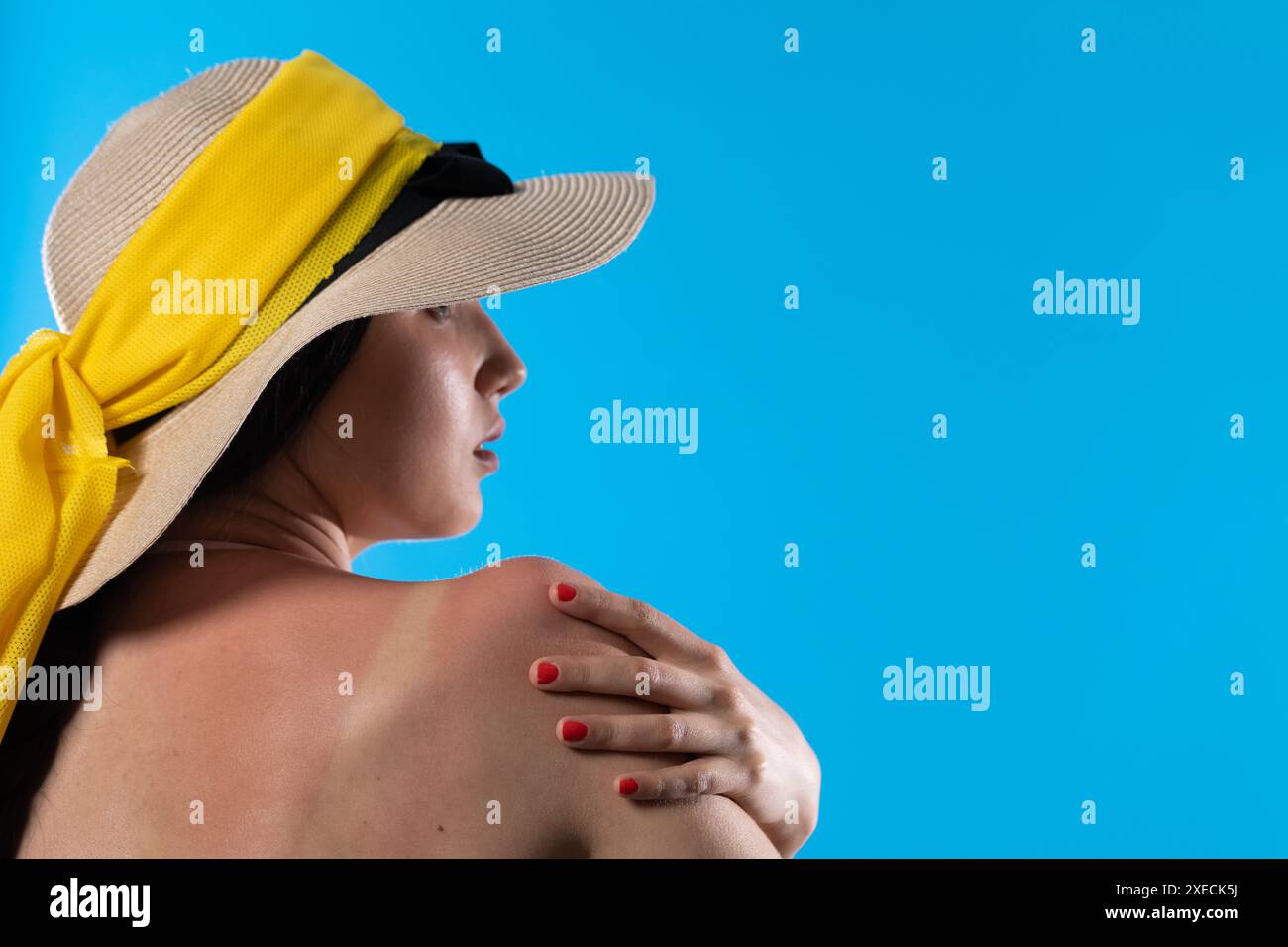 Un adolescente con un grande cappello da spiaggia tiene una mano su una spalla abbronzata. Foto Stock