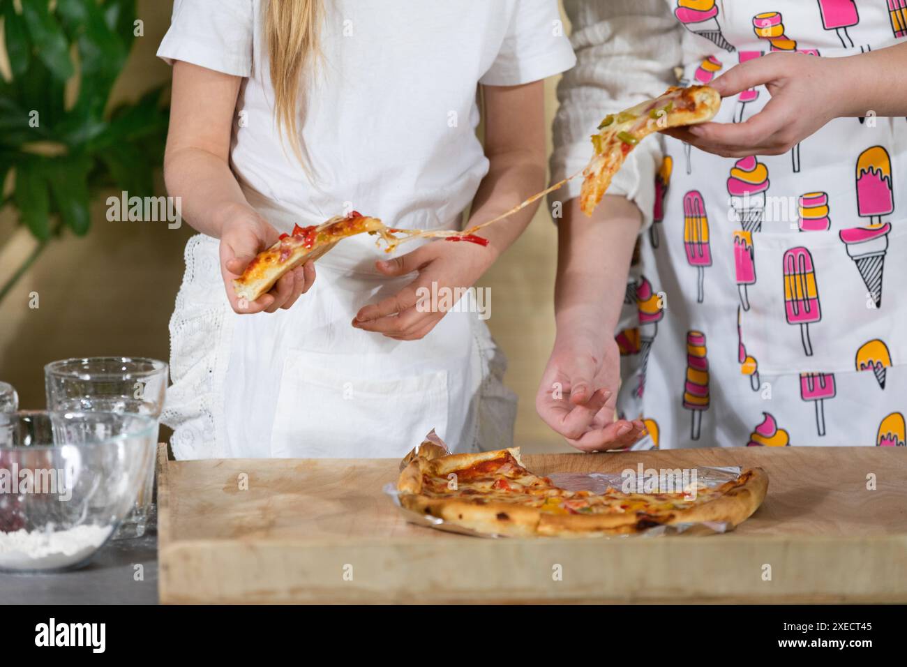 Un primo piano, come una madre con una figlia di cinque anni, è separato da pezzi di pizza, che hanno cucinato loro stessi Foto Stock